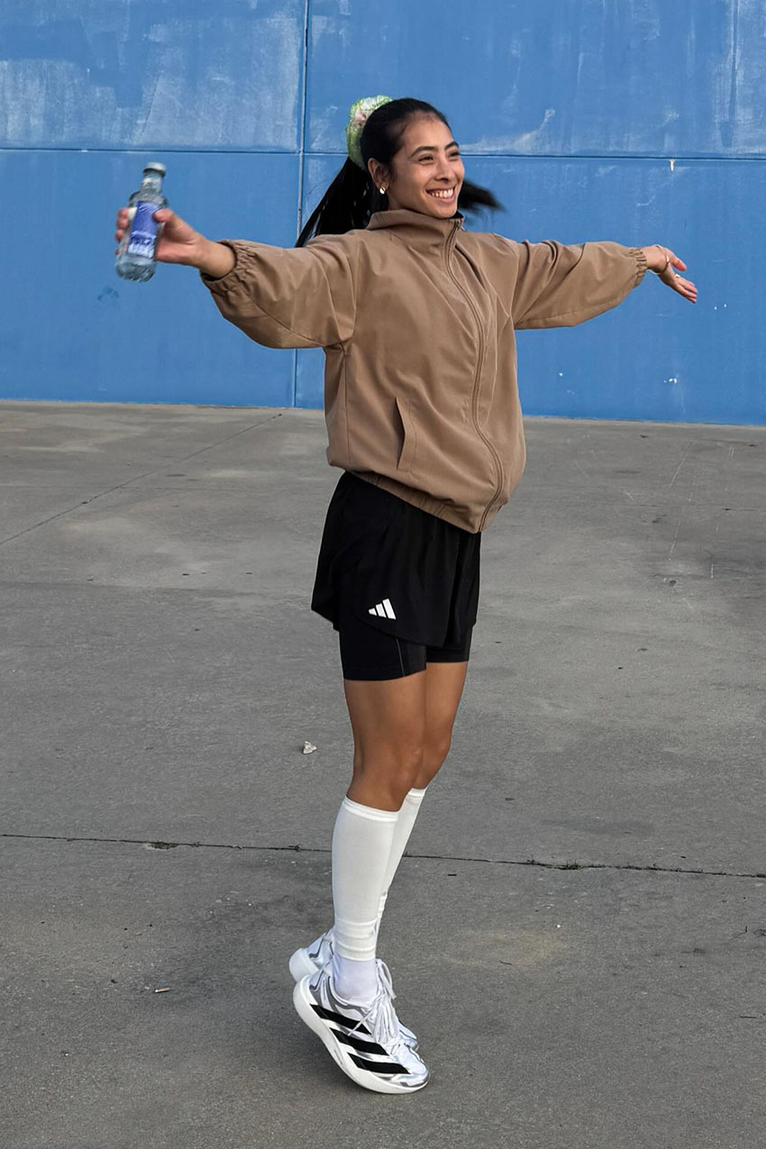 a woman wearing a brown jacket, black shorts, and chunky sneakers