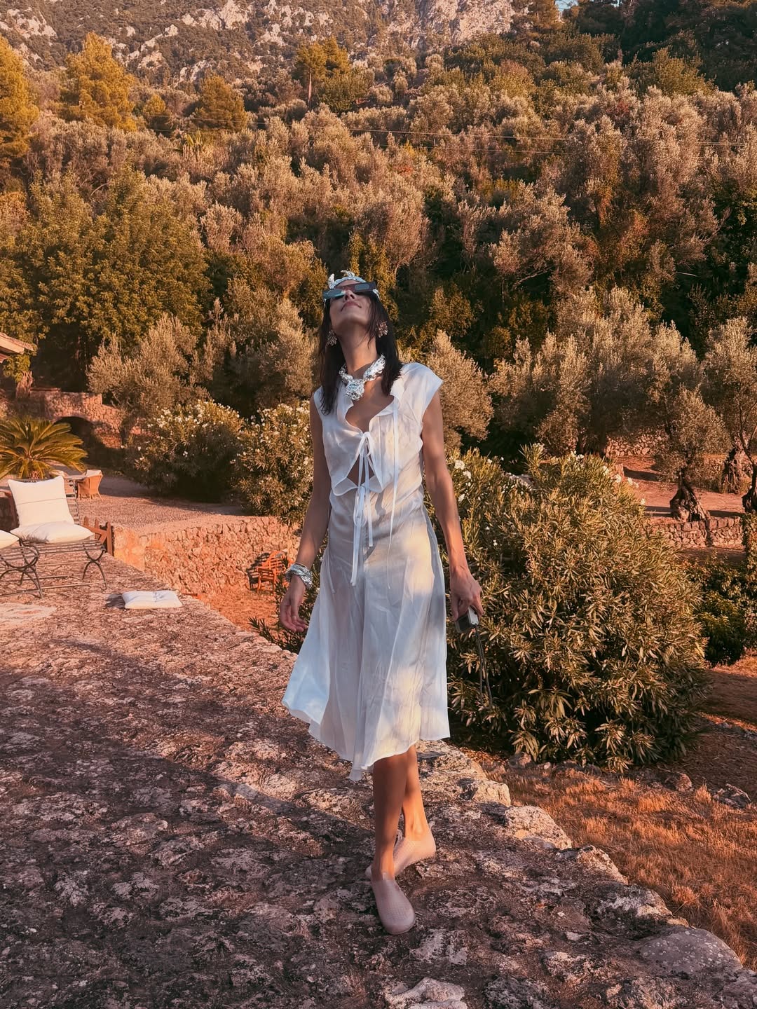 Alexa Chung wears transparent water shoes with a white cotton midi dress and sunglasses.