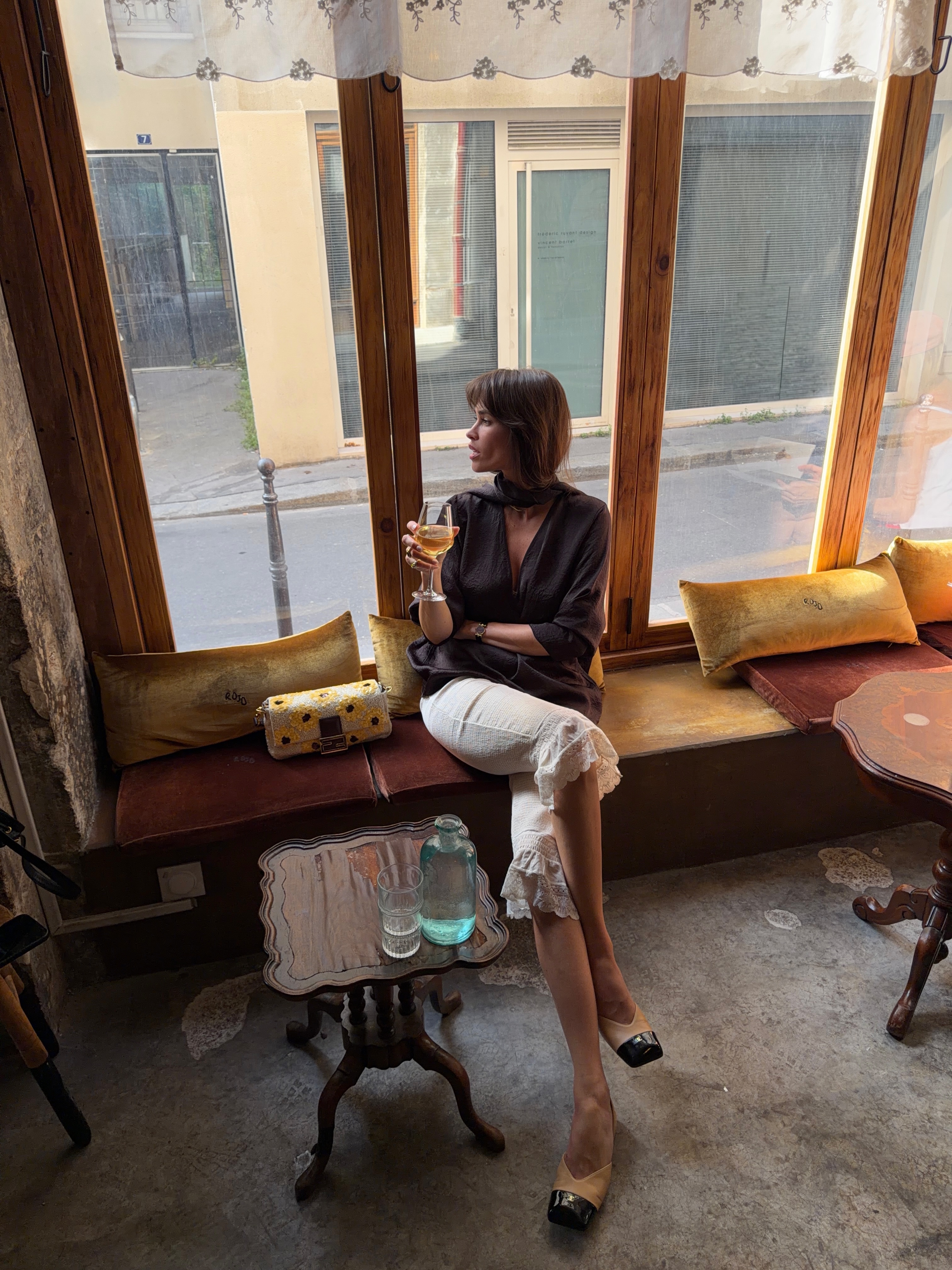 An image of @alisontoby wearing long ruffle-trim shorts with a black blouse and Chanel two-toned heels.
