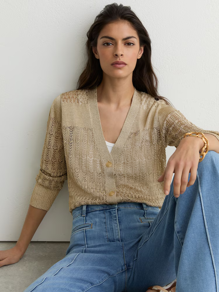 A model wearing a metallic crochet Reiss cardigan with jeans.