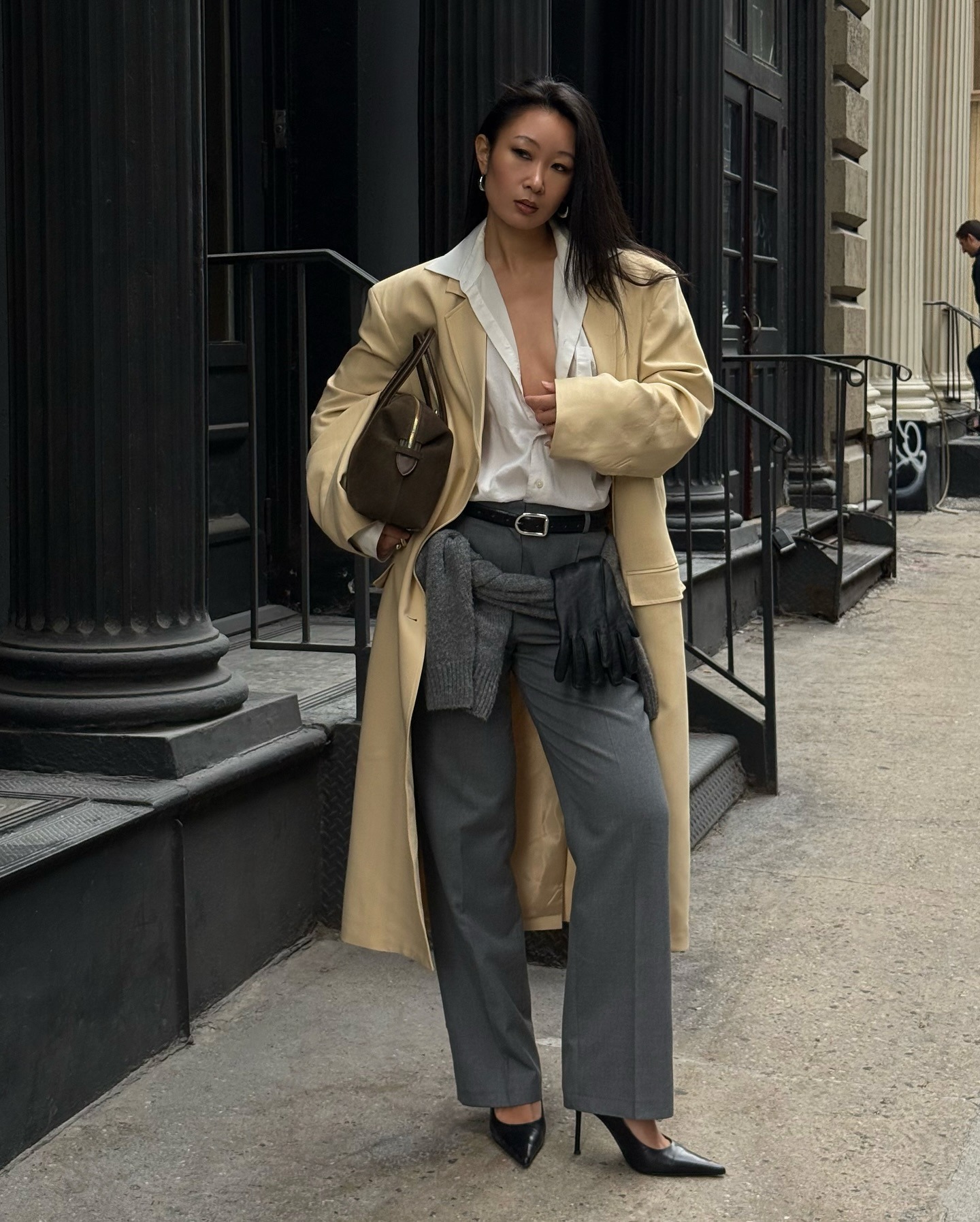Woman wears beige coat, white shirt, grey trousers and black heels