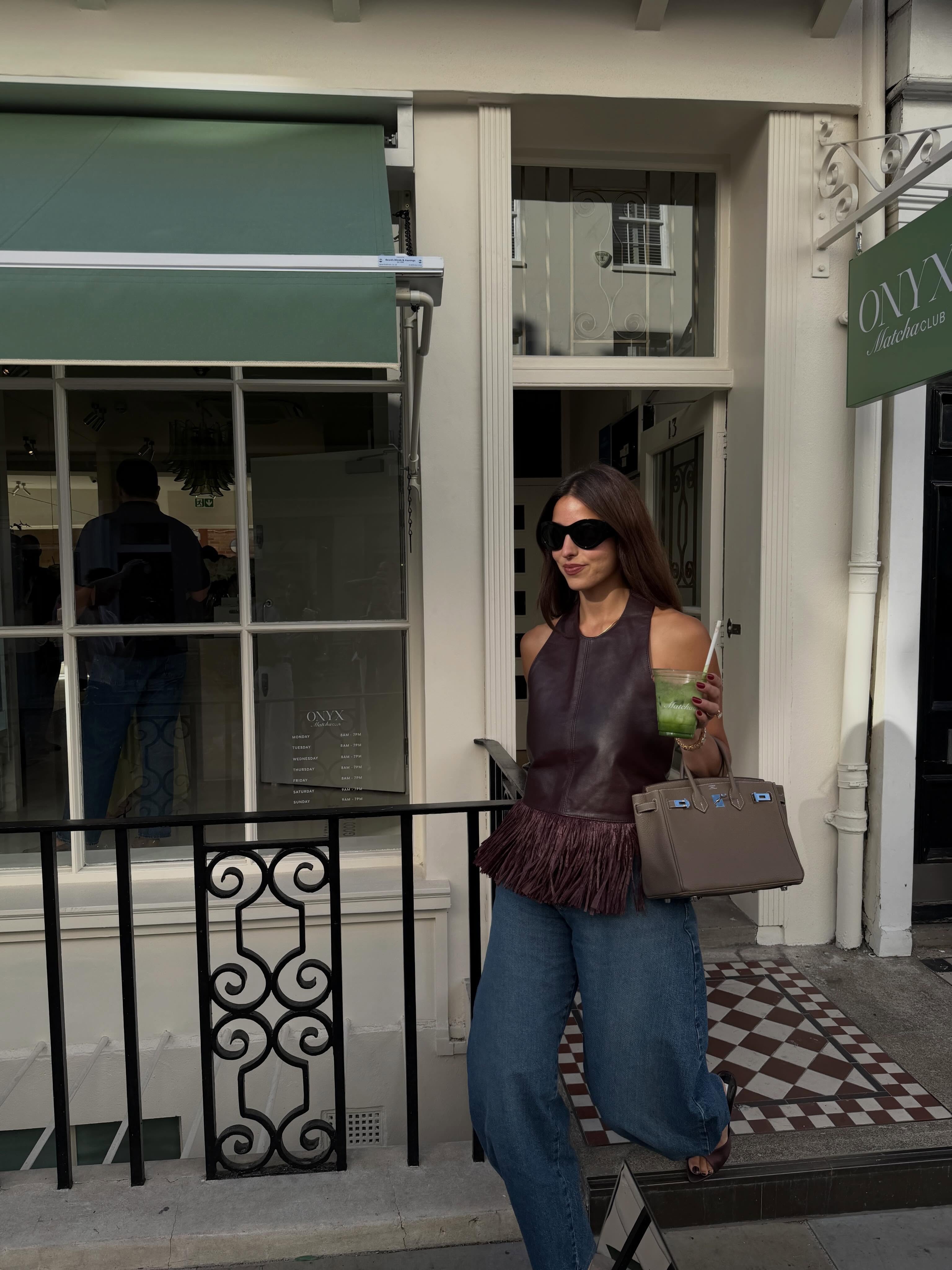 Influencer Bettina Looney wearing a fringed leather halterneck top, barrel leg jeans and kitten heel mules.