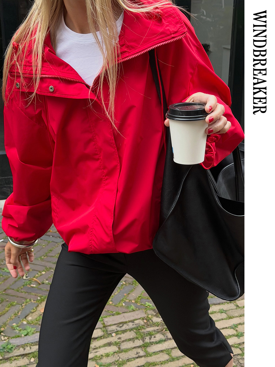Woman wearing a red windbreaker and black pants