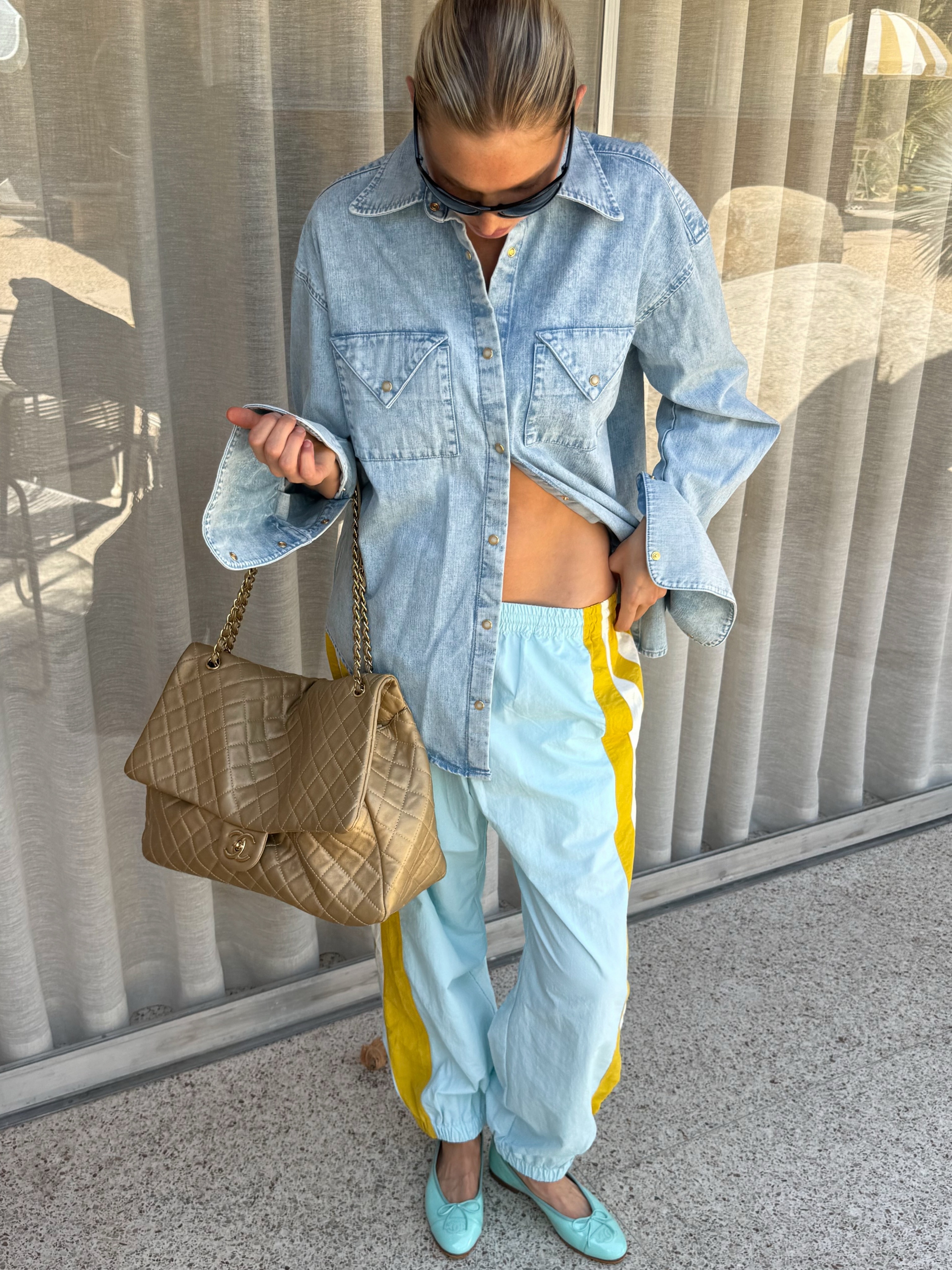 Elsa Hosk wearing a denim shirt, light-blue balloon track pants, a Chanel bag, and Chanel aqua ballet flats