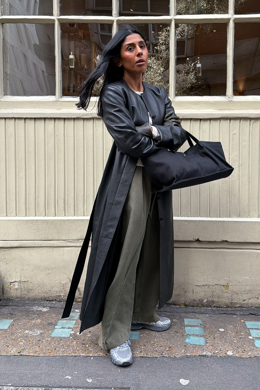 a woman wearing a leather trench coat, olive green pants, and chunky sneakers