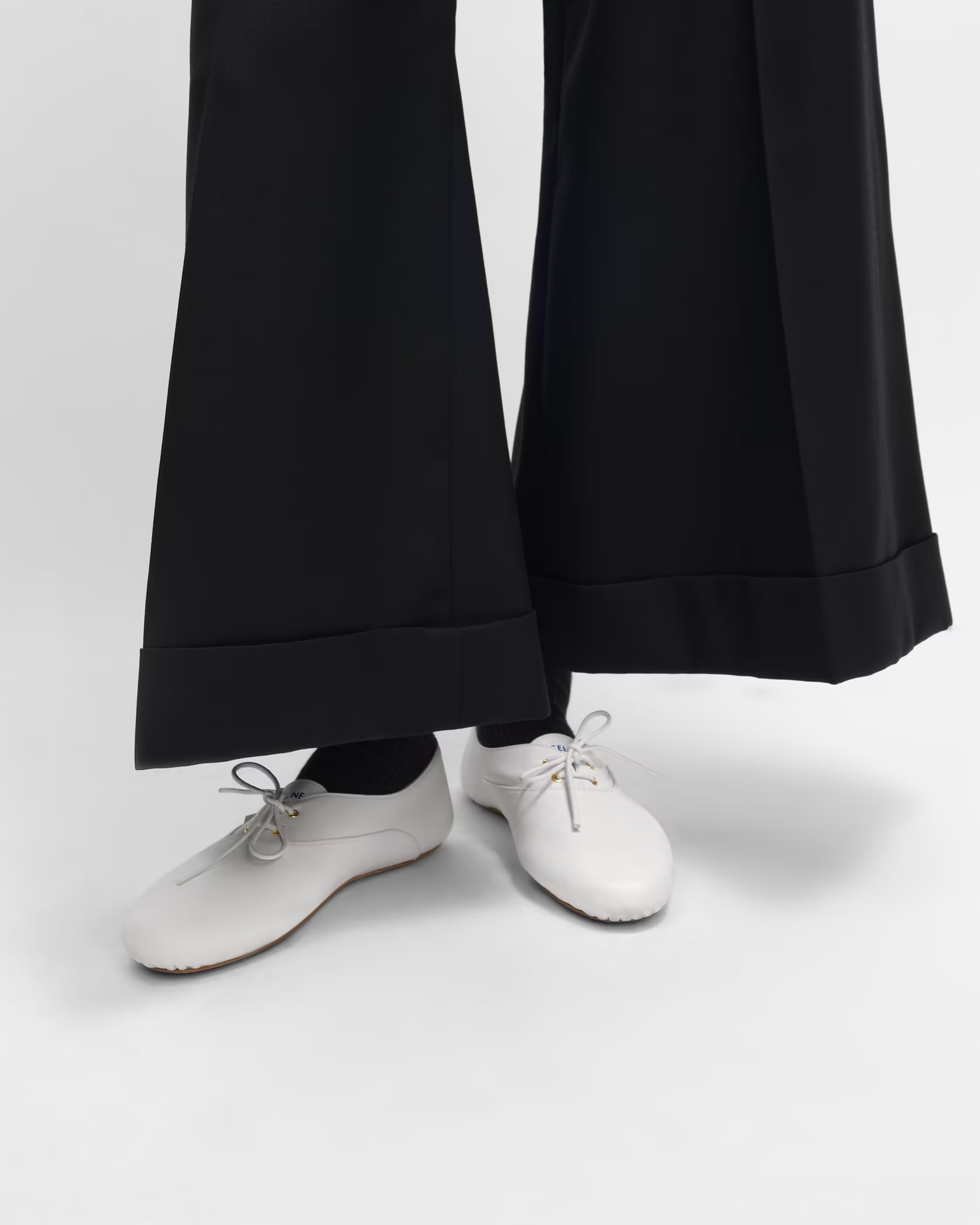 A model wearing white Celine jazz flat shoes.