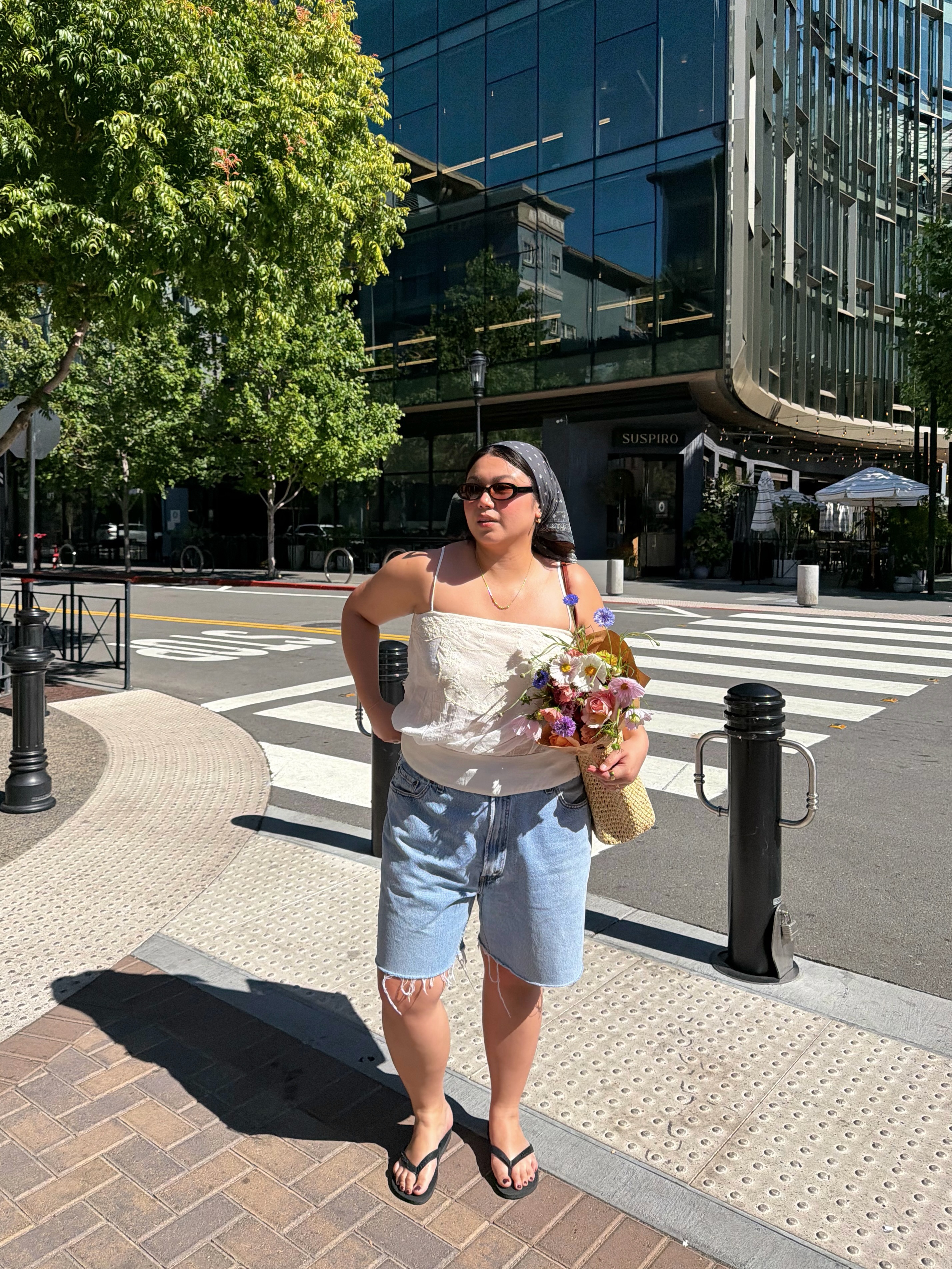 A woman wearing long, loose denim shorts in summer 2026.