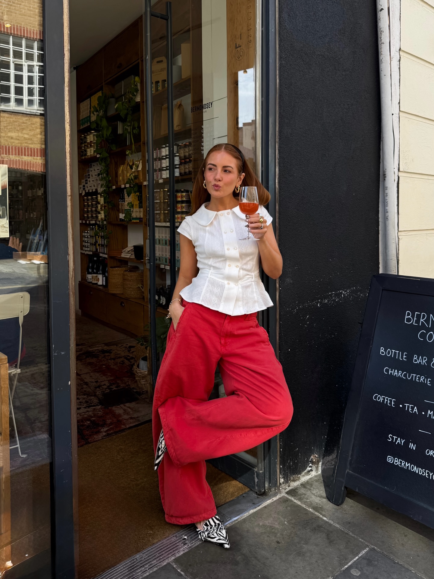Influencer Rebecca Ferraz Wyatt wearing a peplum blouse, red barrel-leg jeans and pointed mules.