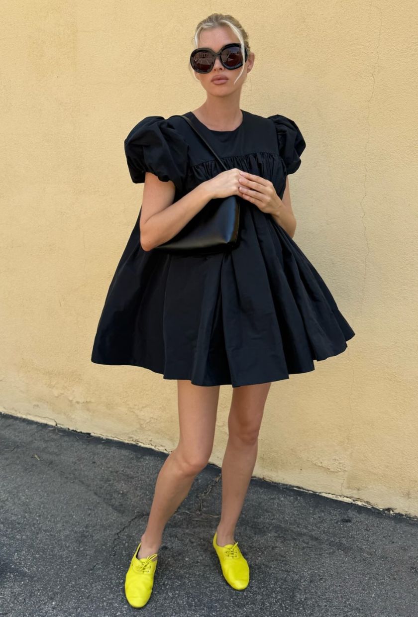 Elsa Hosk wears a black dress, yellow shoes and carries The Row Alma bag