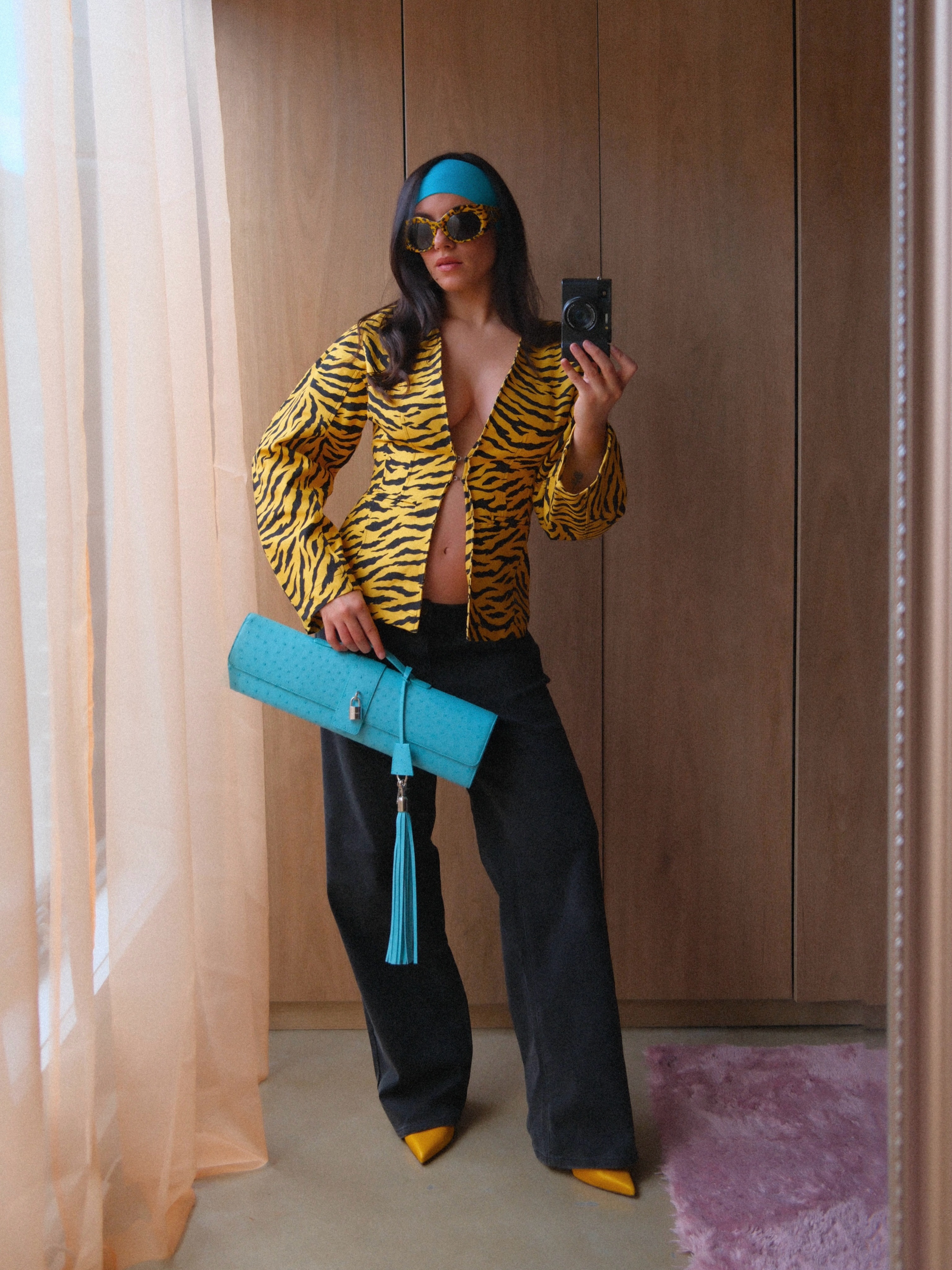 Influencer @maxinewylde takes a mirror selfie wearing a tiger print jacket with a turquoise bag and a turquoise headband.
