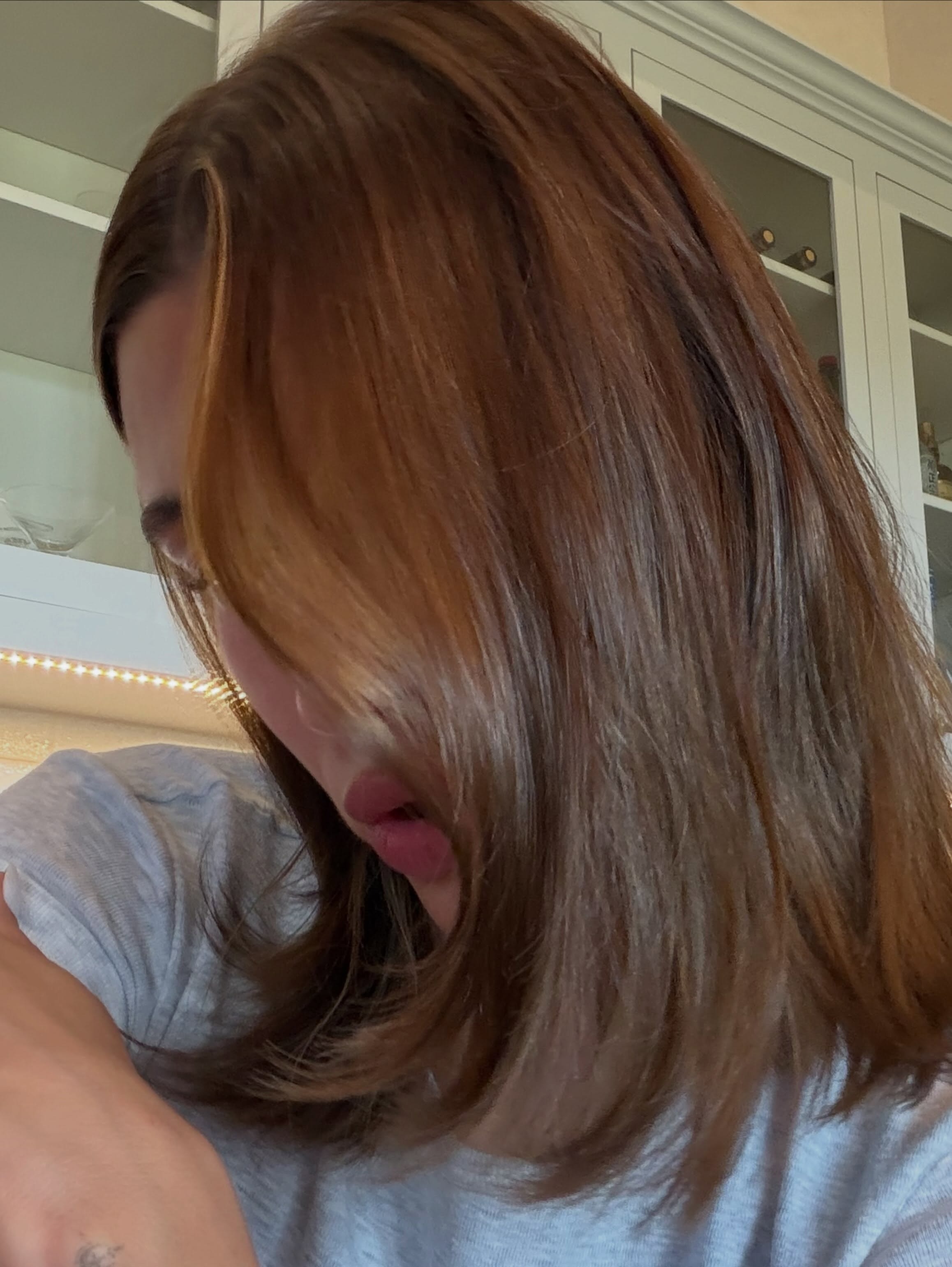 Hailey Bieber taking a selfie with a glossy, burnt amber lob hairstyle