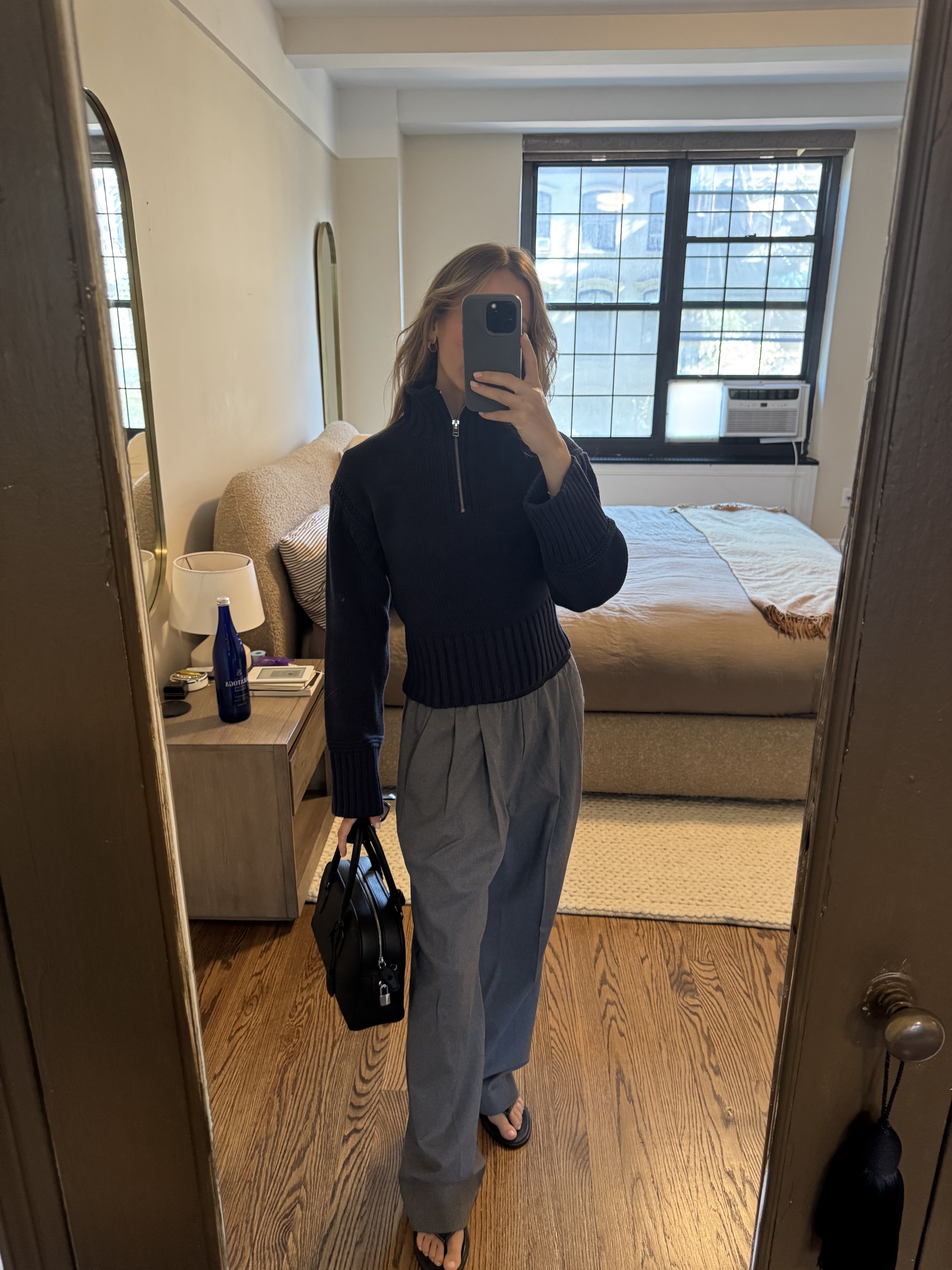 Nikki wears the navy tiny rollneck with gray trousers, black flip-flops and a black bag.