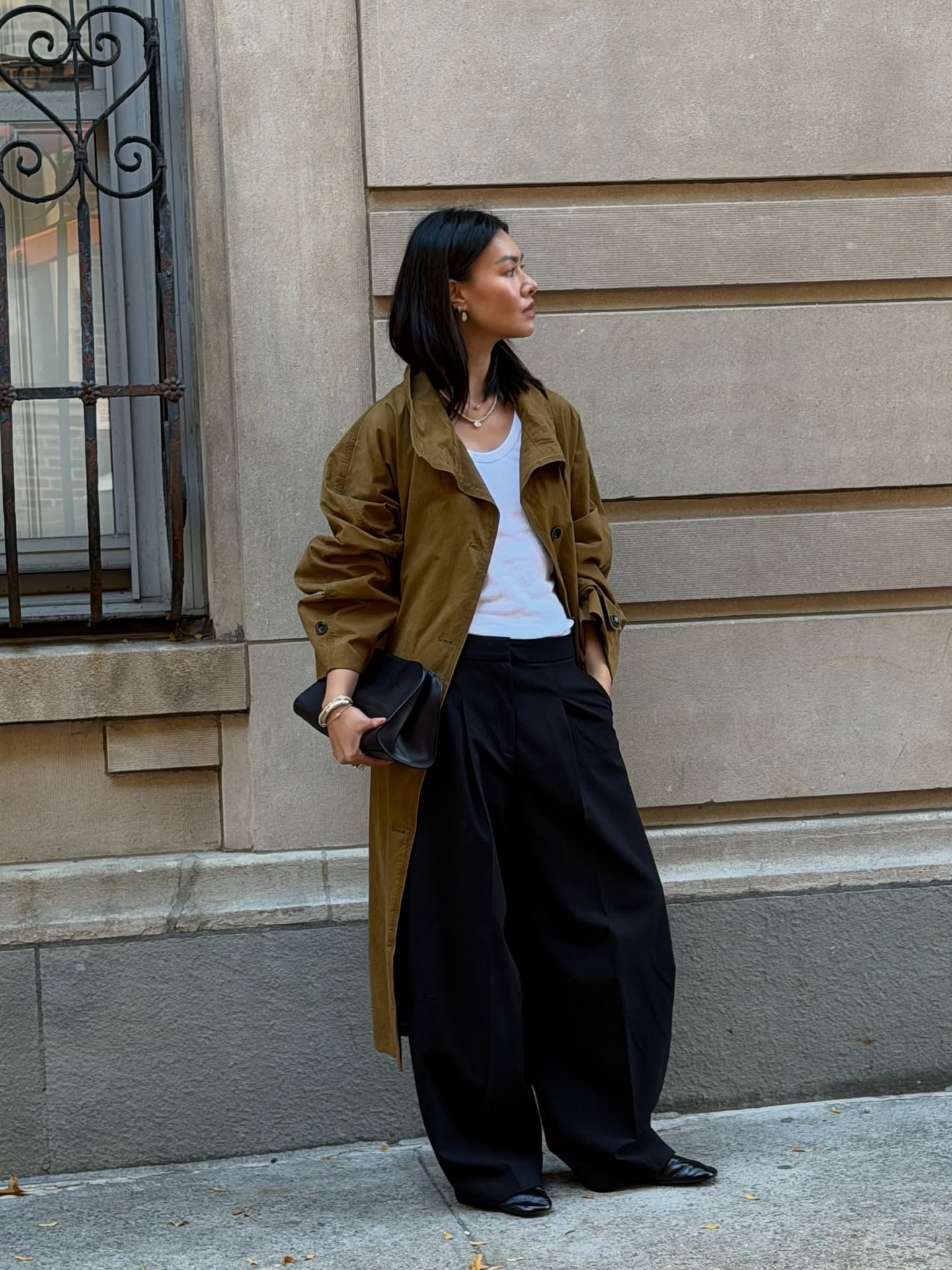 Woman wears trench coat, white top and black trousers