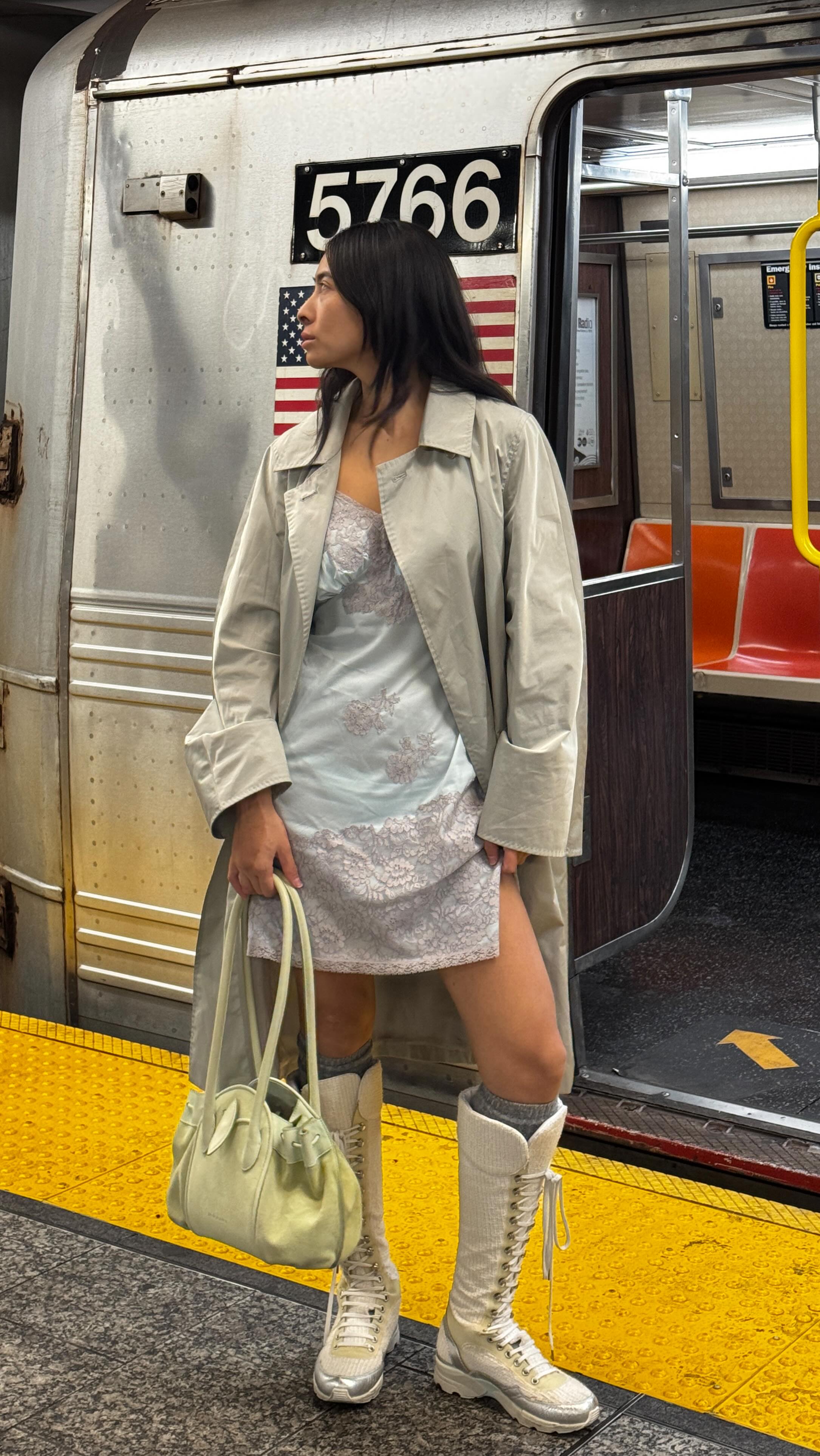 An image of @himichelleli wearing a trench coat with a slip dress and knee-high high-top trainers.