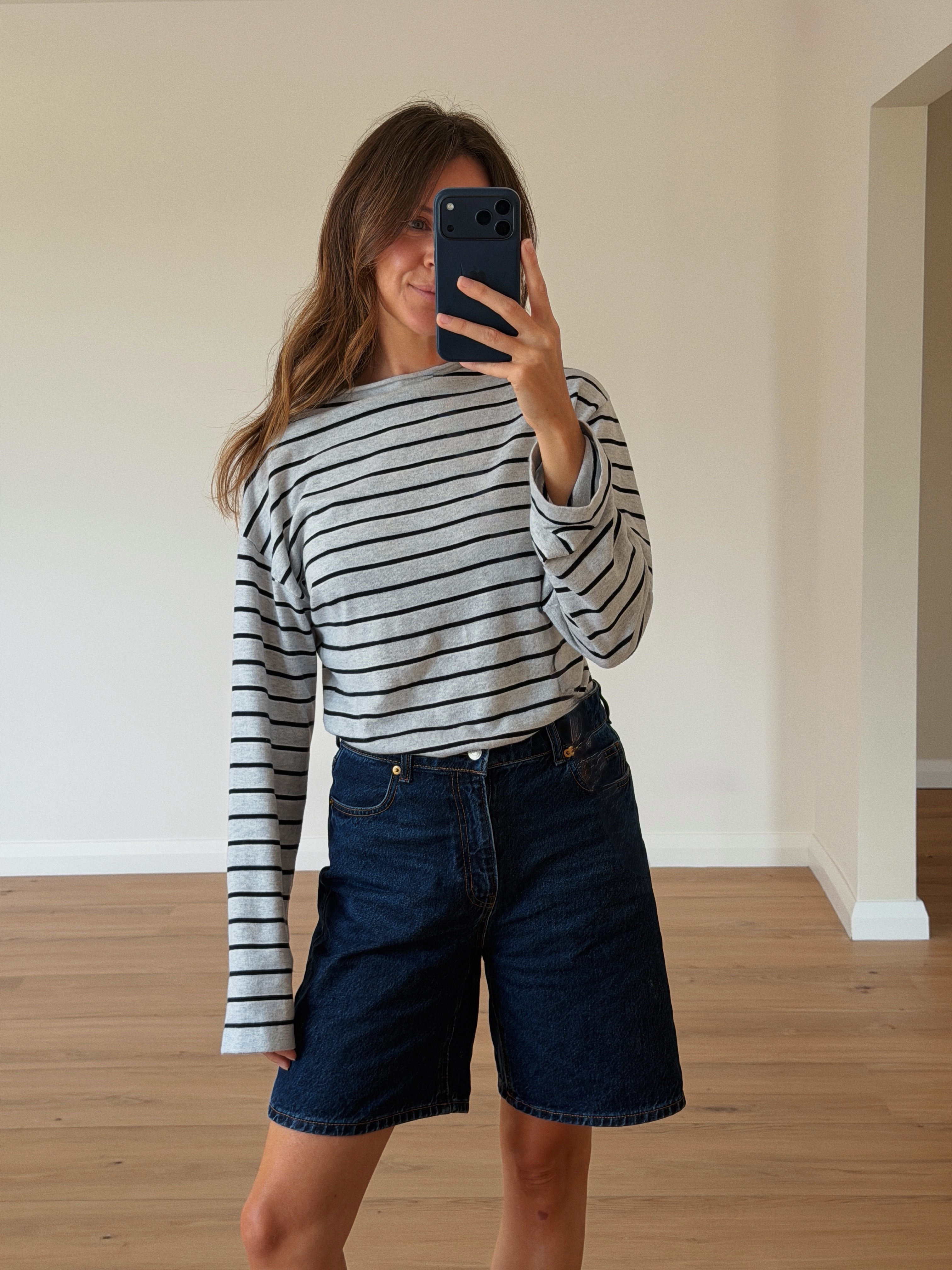 A woman wearing long, loose denim shorts in summer 2026.