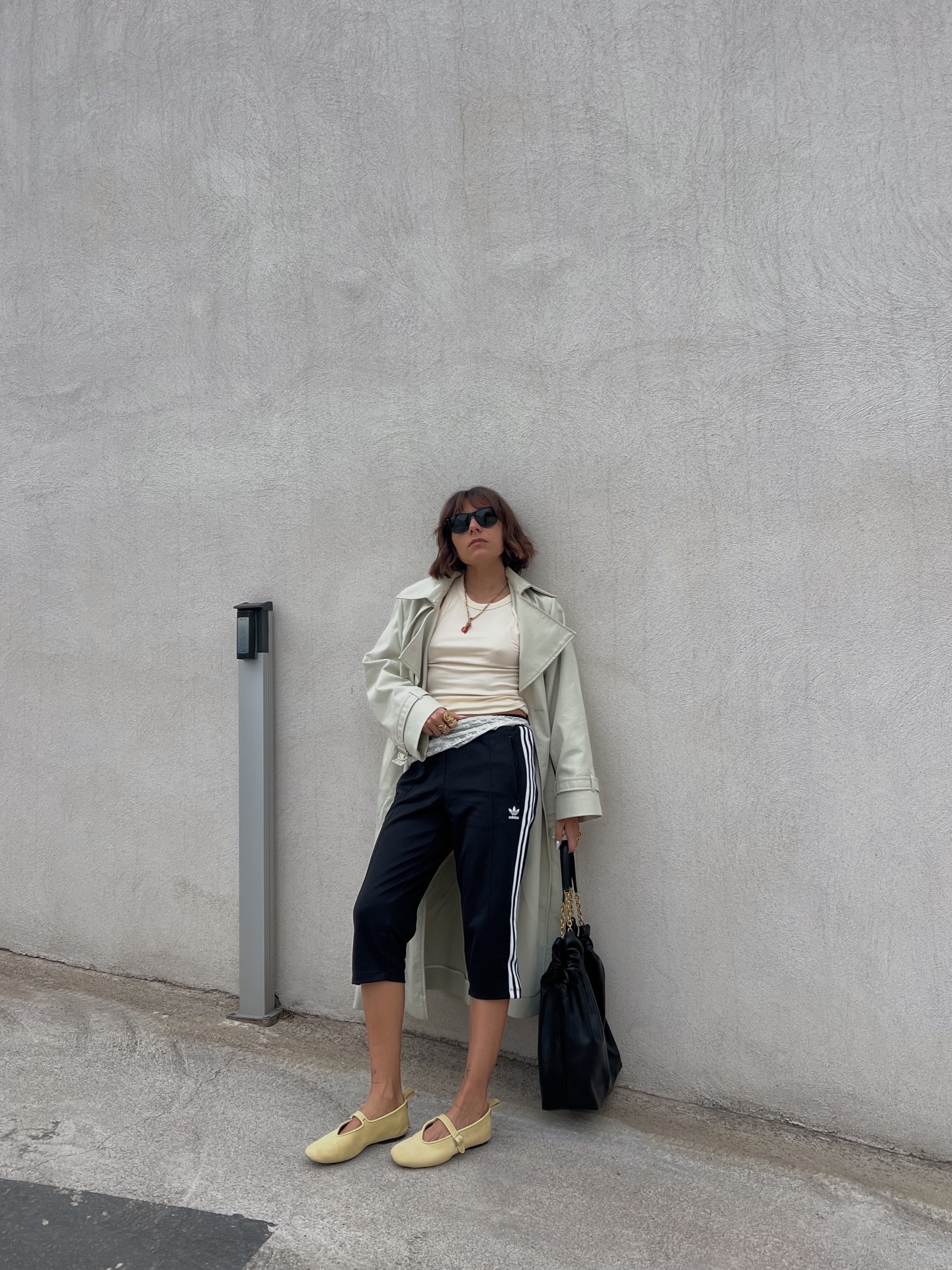 Influencer Emilie T wearing a trench coat, t-shirt, capri pants and ballet flats.