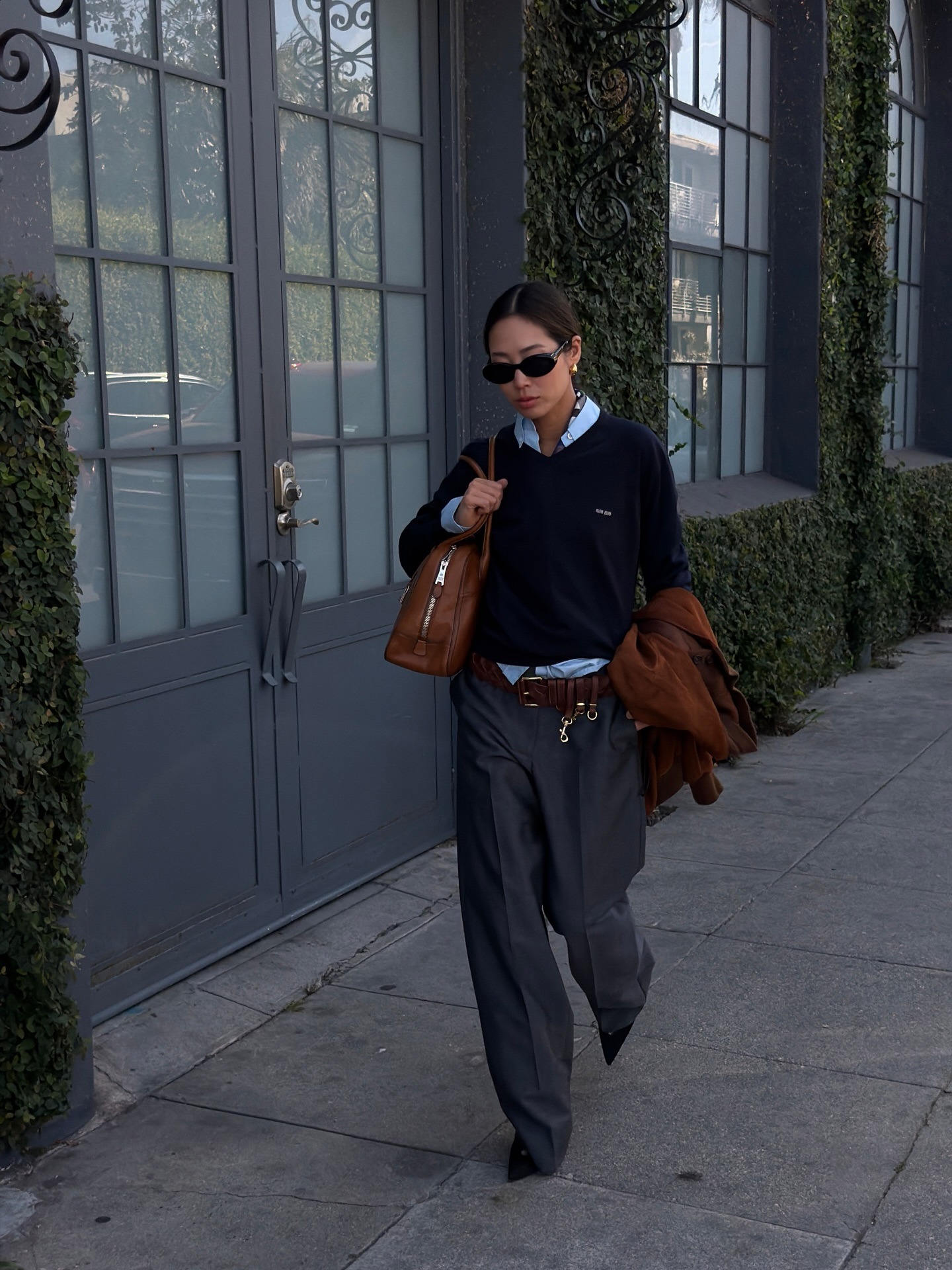 Woman wears knit jumper, shirt, trousers and bag