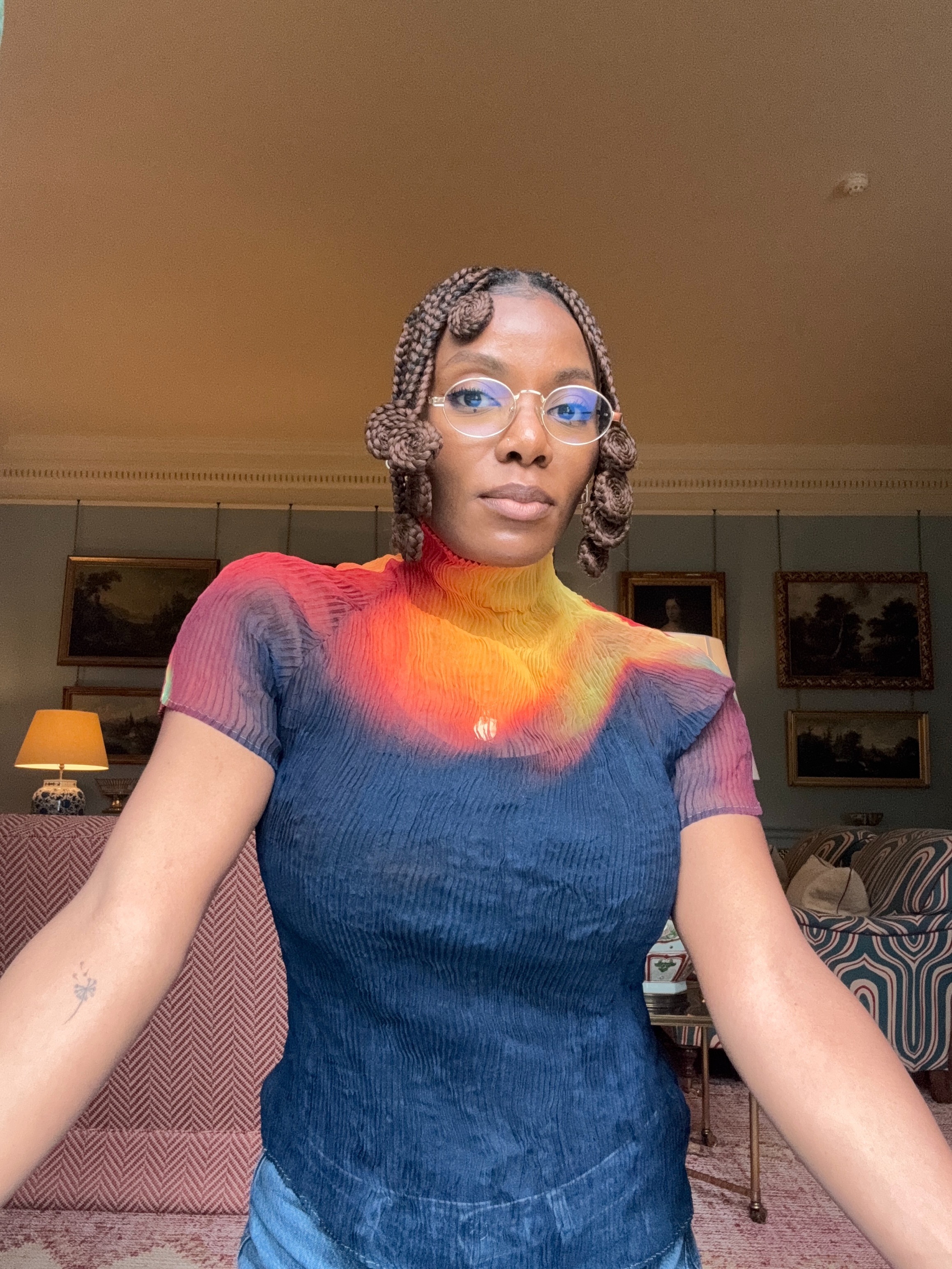 Creator Oluwaseun taking a selfie wearing clear glasses with burnt amber hair