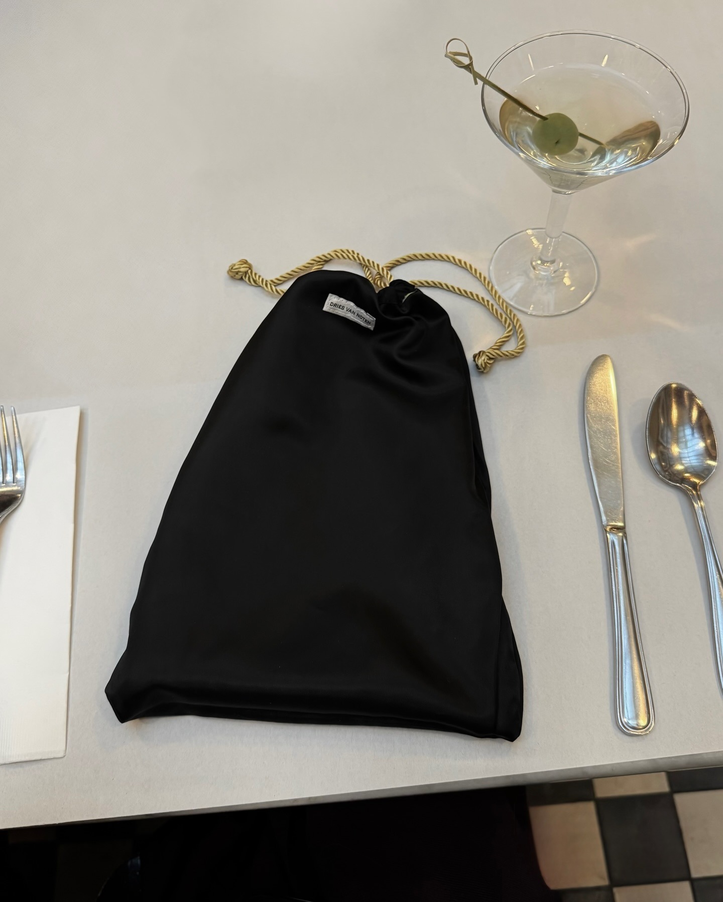 Drawstring pouch sitting on a table next to a martini glass.