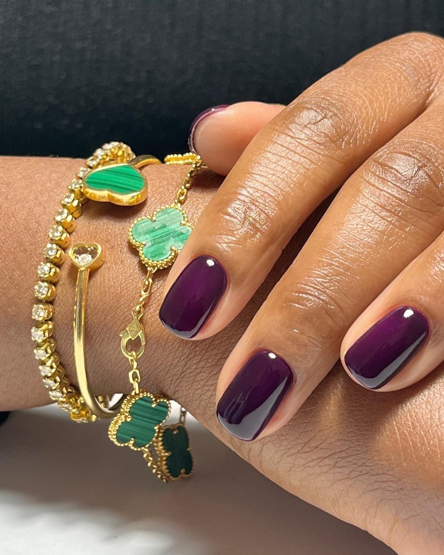 Short nails painted with a deep purple nail colour