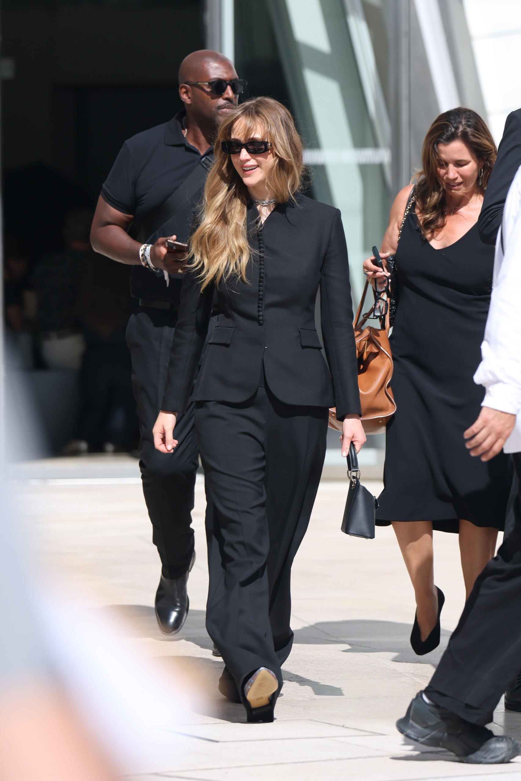 Jennifer Lawrence steps outside in Paris wearing a black single-breasted blazer with black straight-leg trousers and pointed-toe heels.