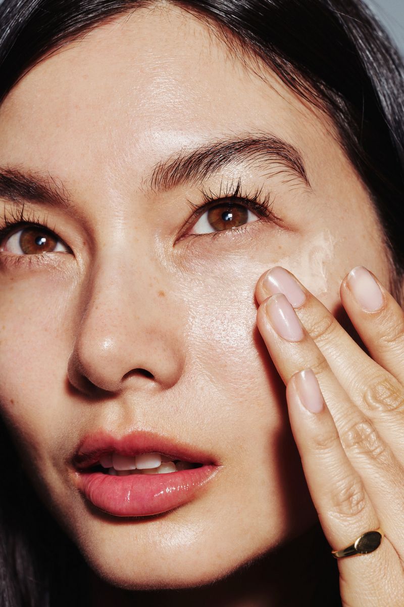 A woman rubbing a cream into her skin