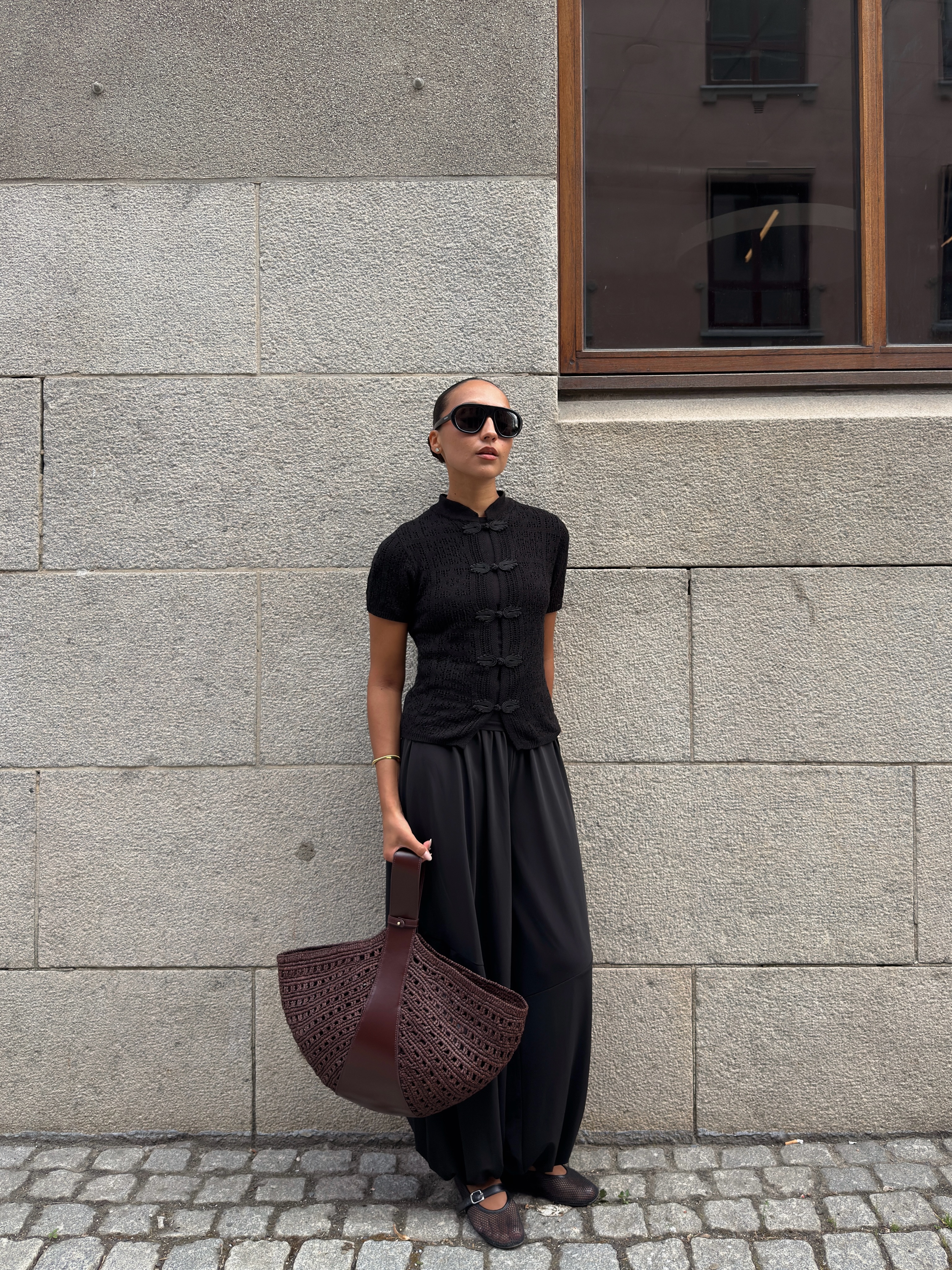 Influencer Ingrid Edvinsen wearing a black short sleeve shirt, black balloon trousers, ballet flats and large tote bag.