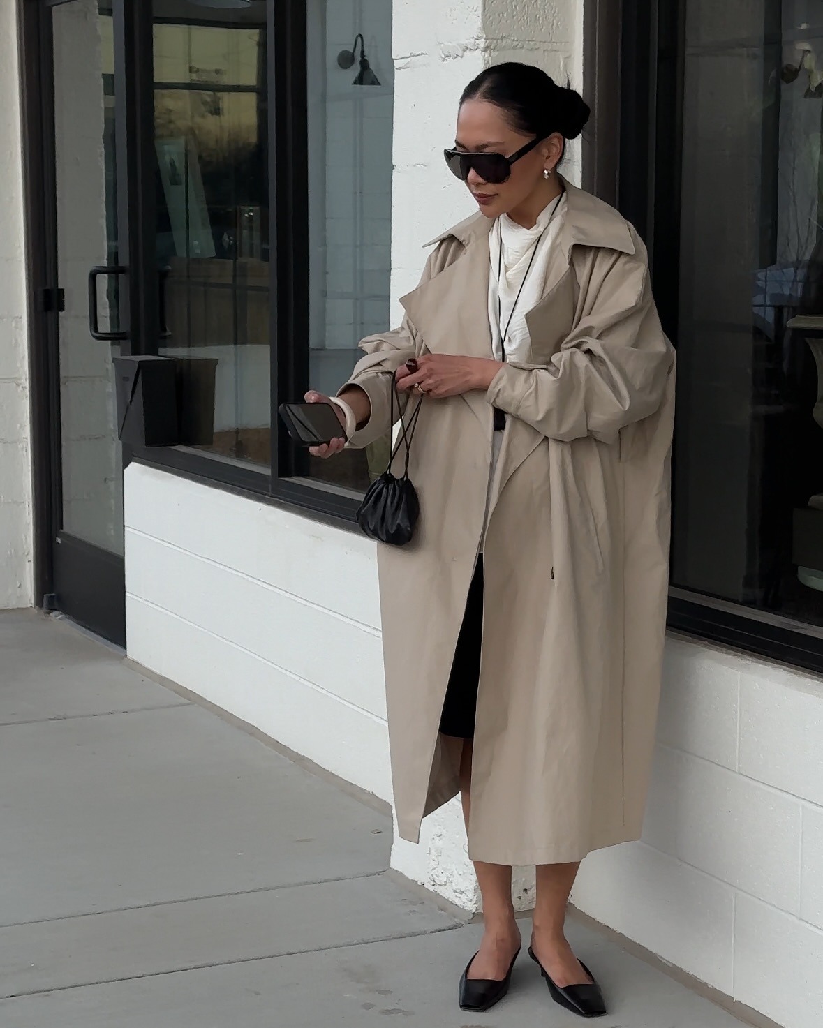 @dawn.tan wearing a trench coat and drawstring pouch.