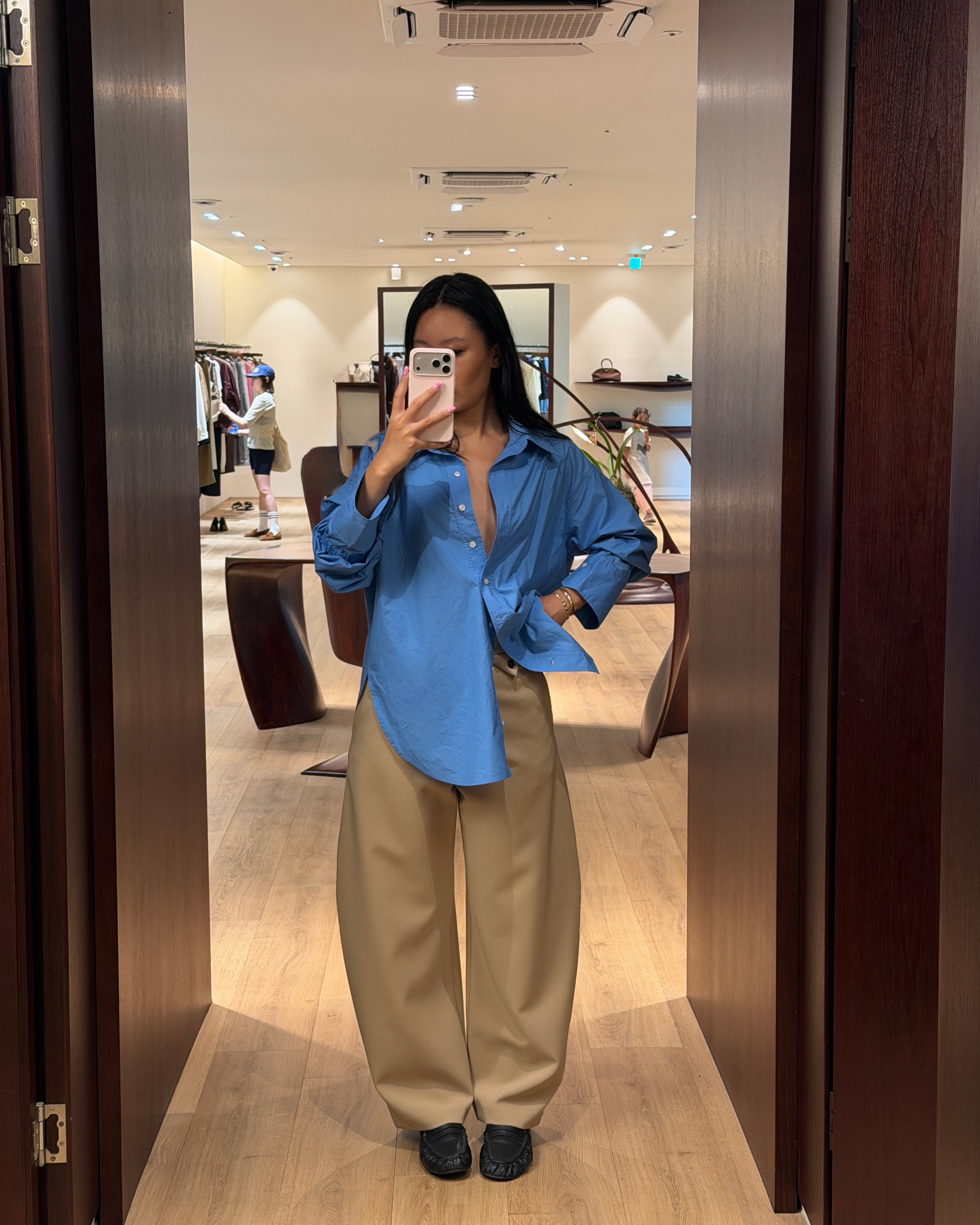 Influencer Caroline Lin wearing a blue shirt with beige barrel-leg trousers.