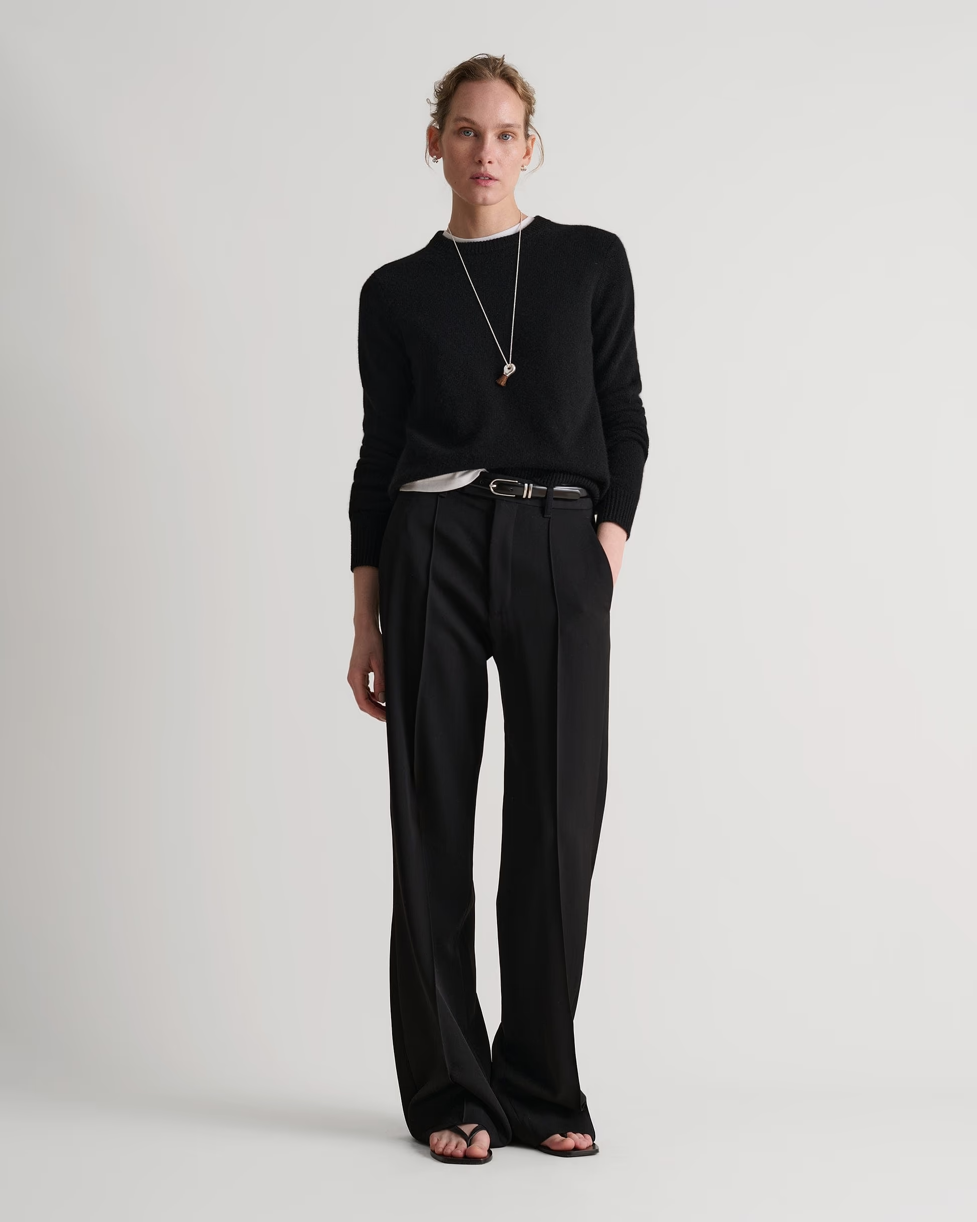 A model wearing a black crew neck Rise & Fall jumper.