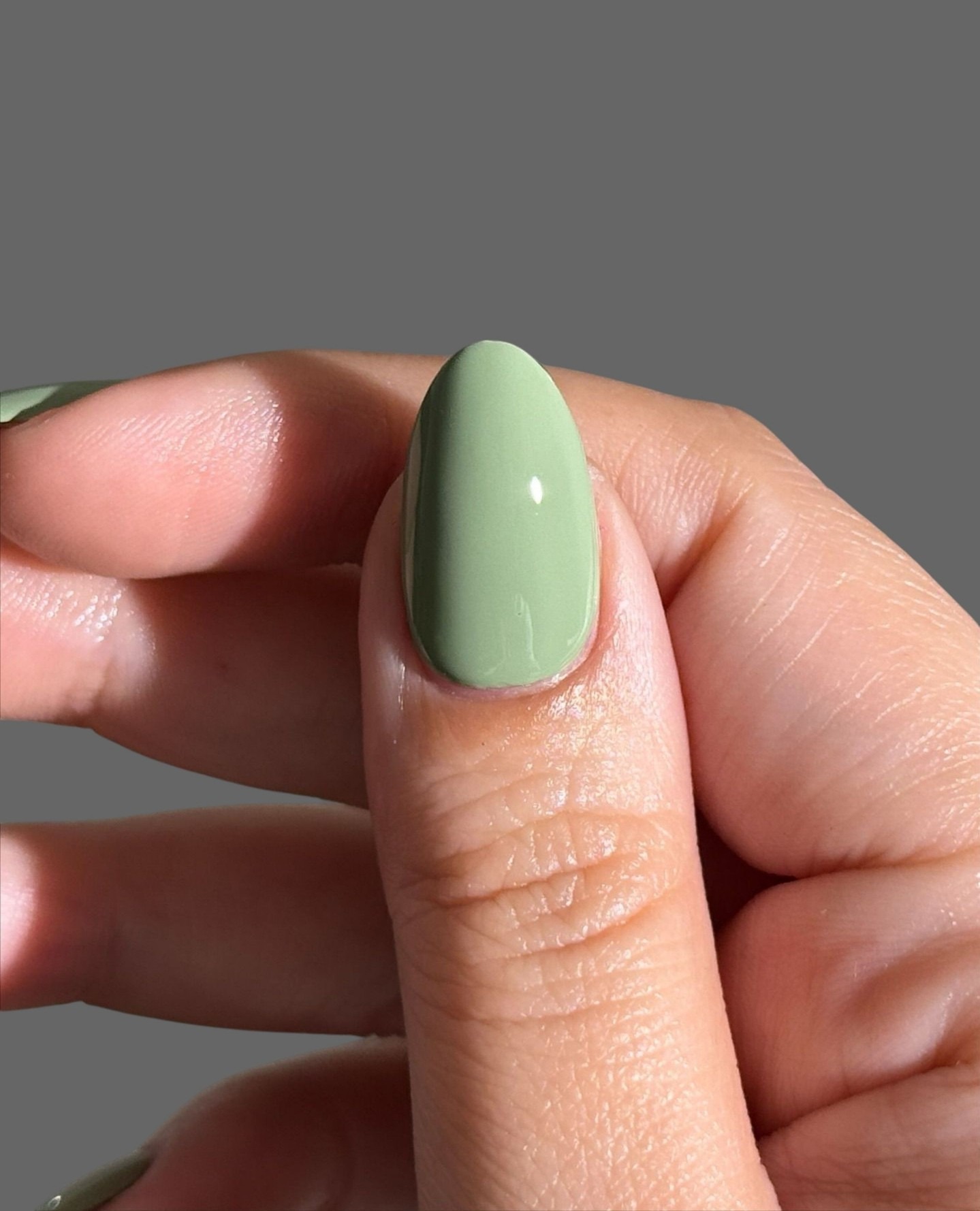 A close-up of a milky green manicure