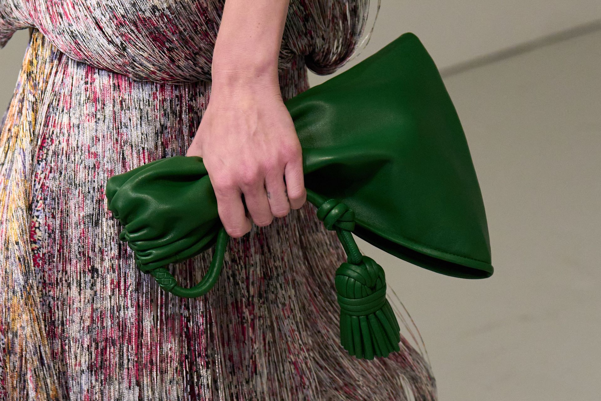 A model walking in the spring/summer 2027 Bottega Veneta show during Milan Fashion Week carrying a green pouch handbag.