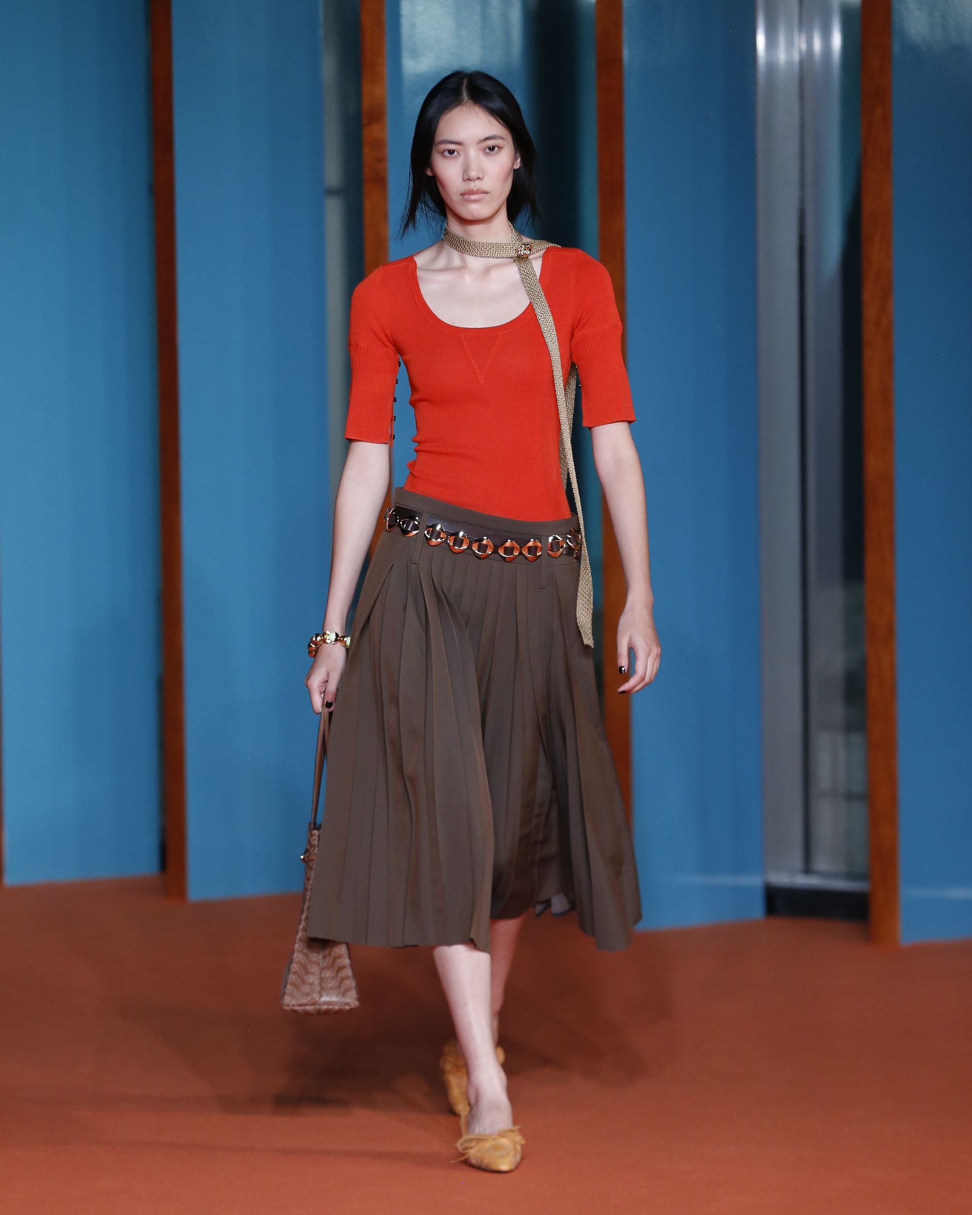 Tory Burch ss27 runway model wears skirt, red top, coin belt