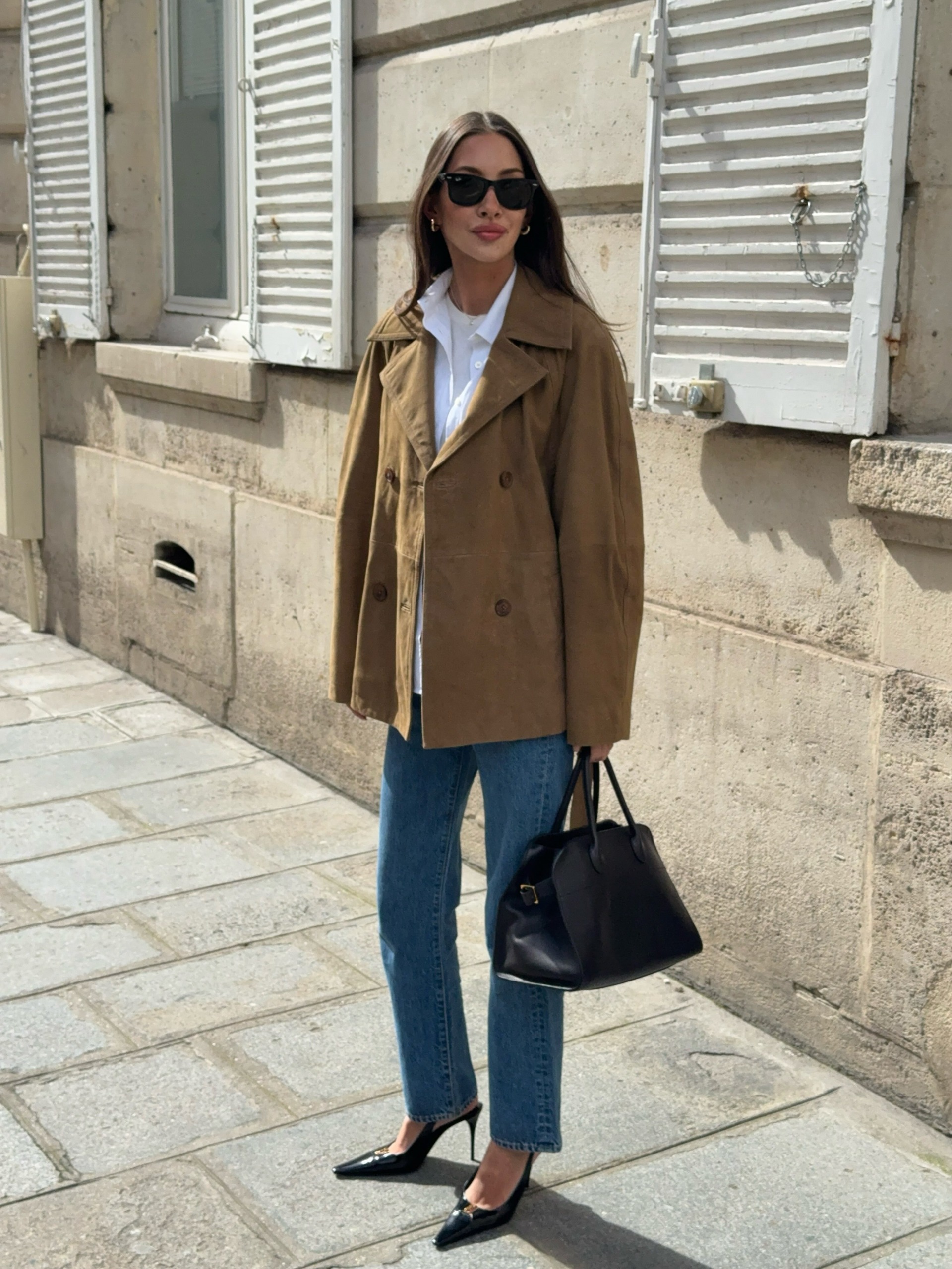 Woman wears suede jacket, blue jeans and black bag