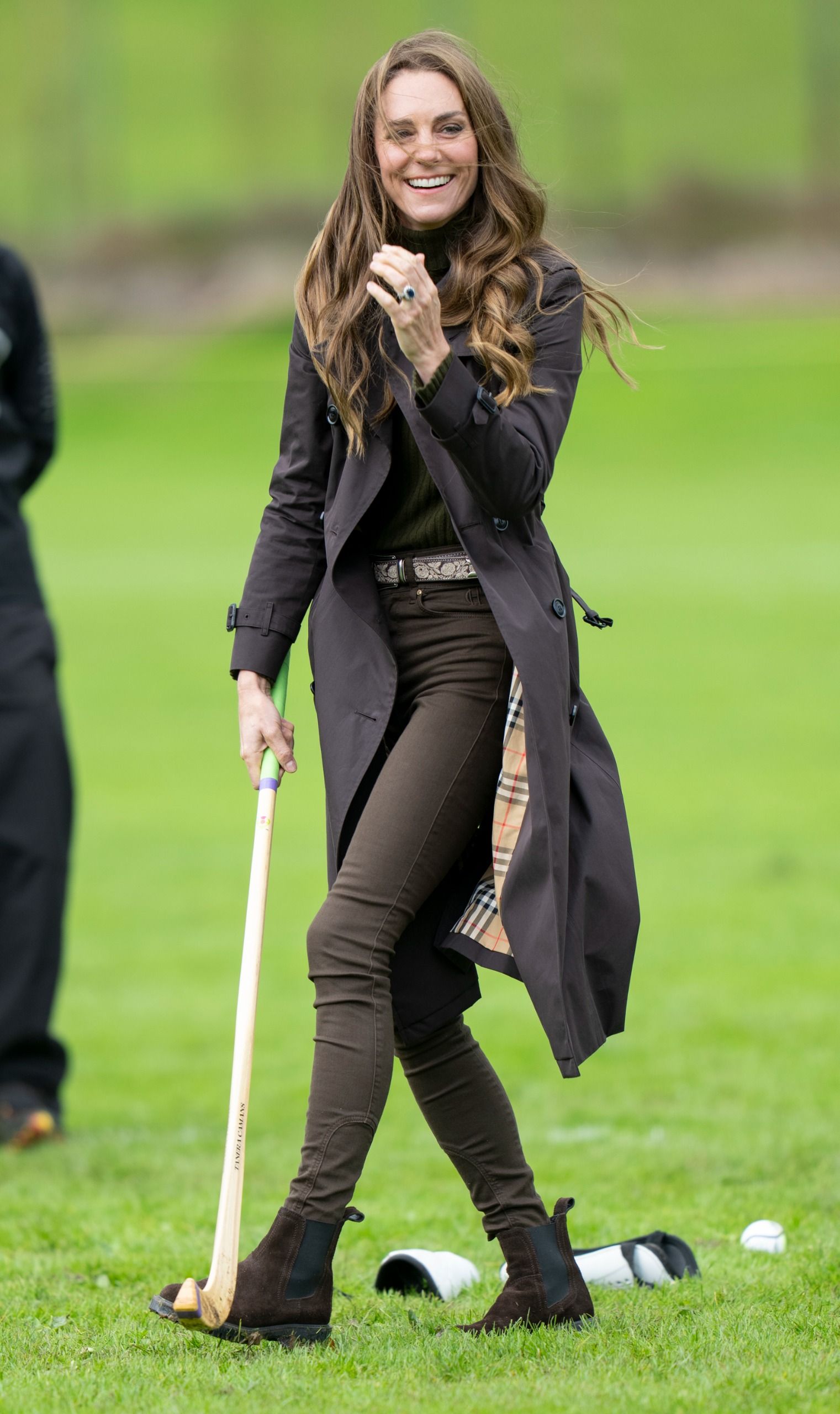 Kate Middleton wears brown skinny jeans and a green turtleneck sweater with a Burberry trench coat