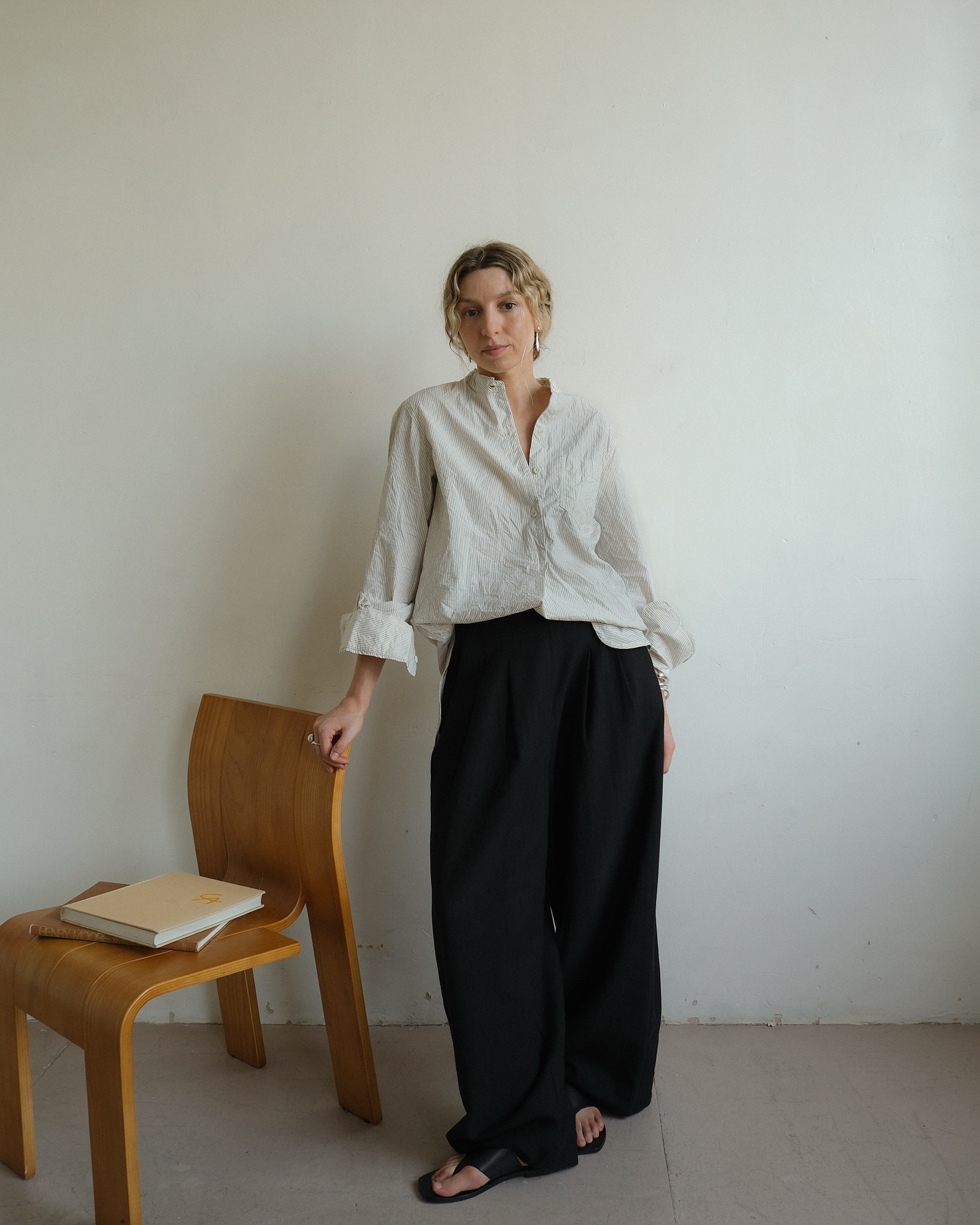 brittany bathgate wears an off white shirt, black wide leg trousers and sandals