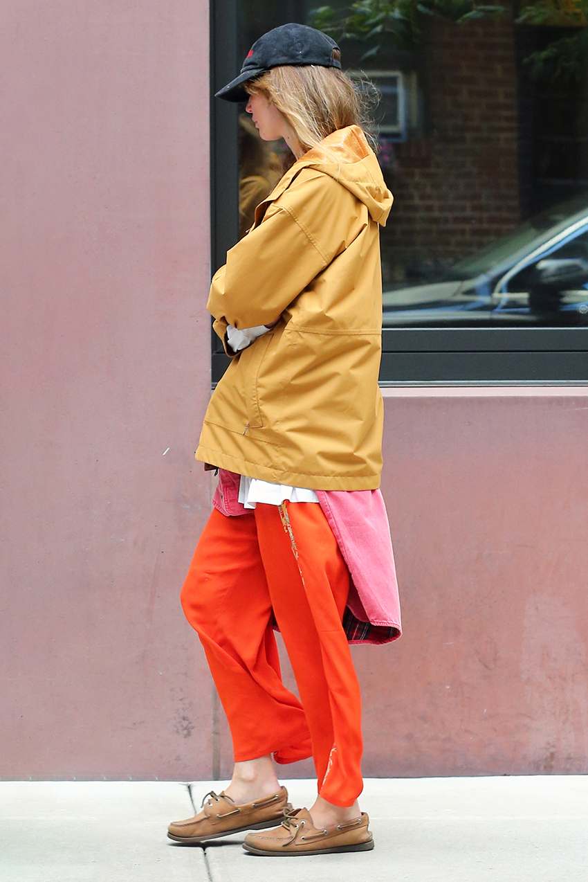 Jennifer Lawrence in NYC wearing a yellow windbreaker, red pants, boat shoes, and a black baseball cap