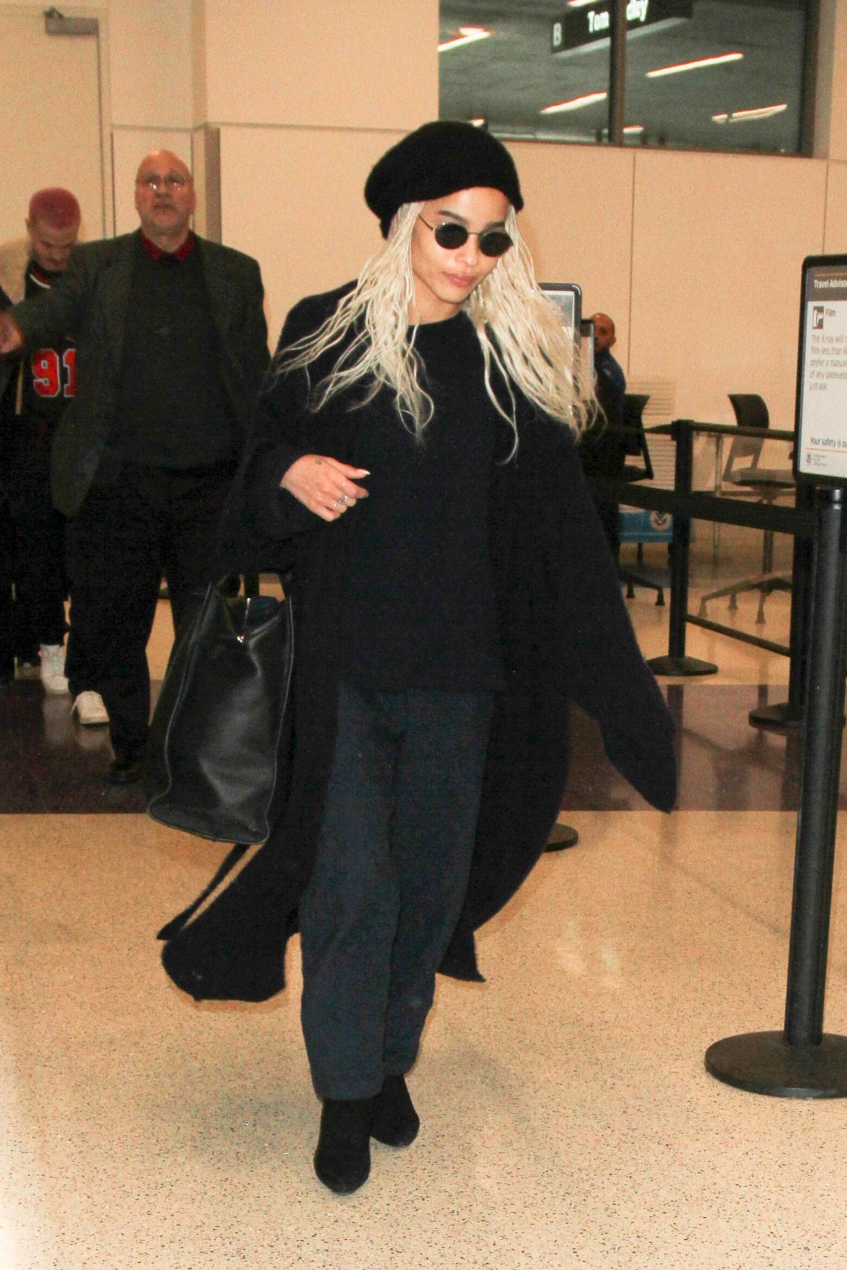 Zo&euml; Kravitz wearing a black jumper, black joggers, blaxk coat, black boots and beret at the airport.