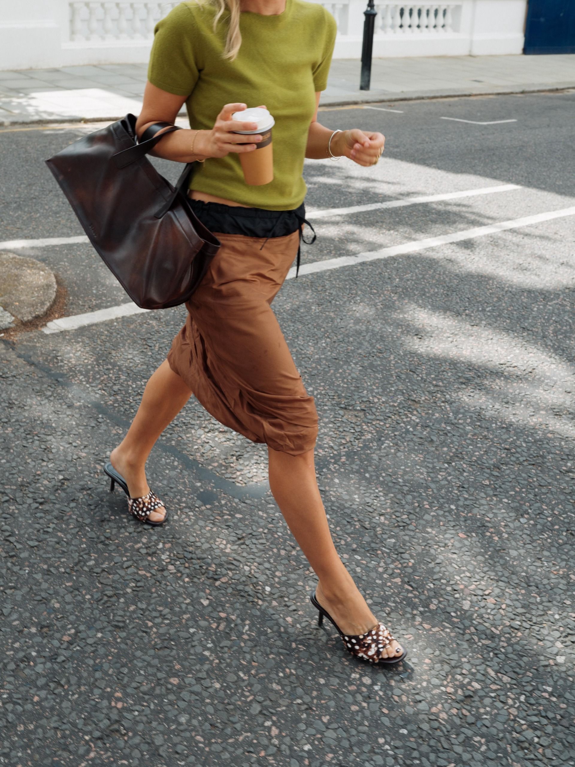 An image of an influencer wearing a green short-sleeve top and brown midi skirt with Dalmatian print heels