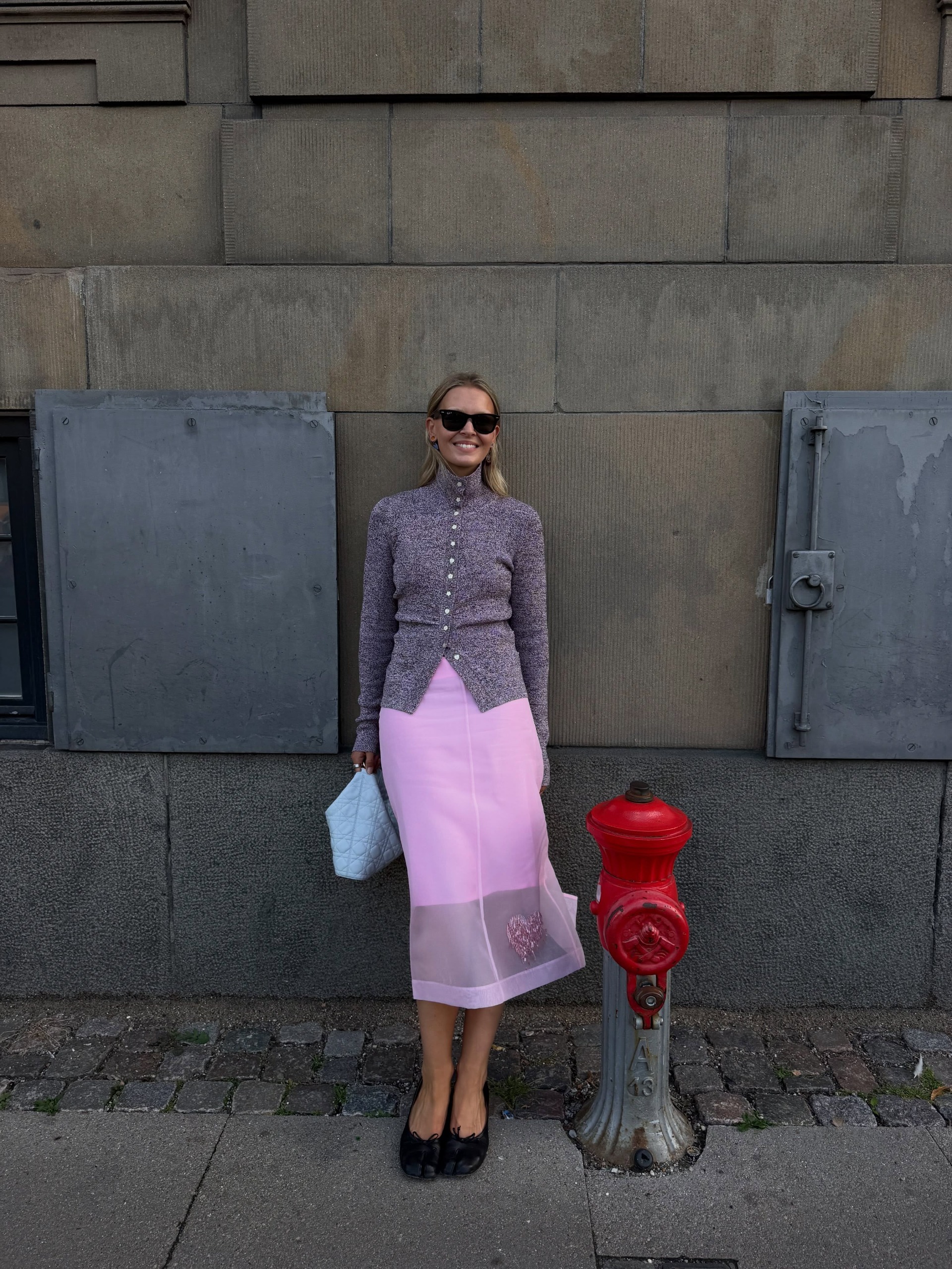 Influencer Hollie Mercedes wearing a turtleneck cardigan with pink sheer skirt.