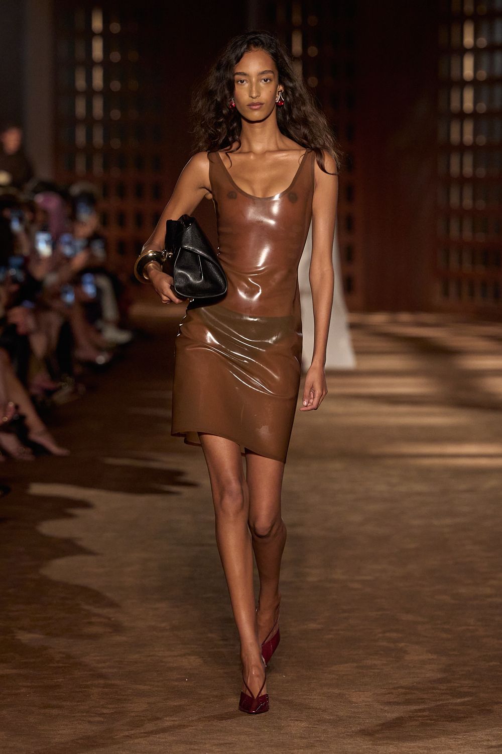 a model wears latex while walking the ferragamo spring 2027 runway.