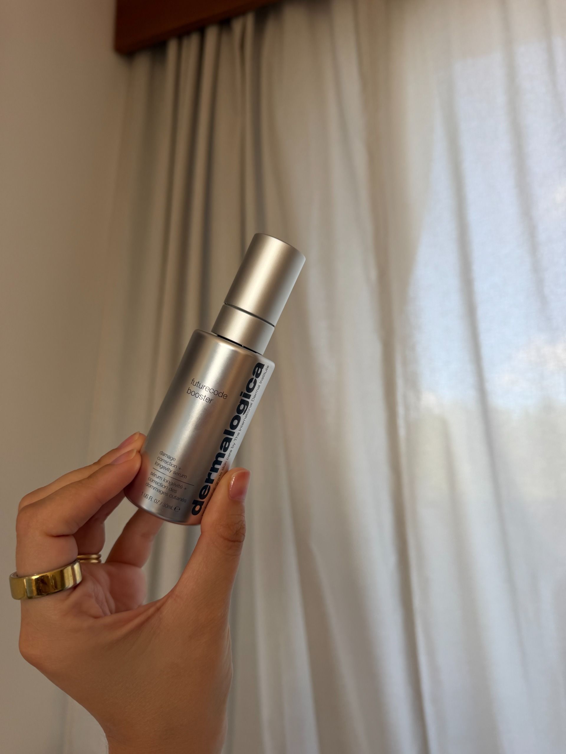 Shannon Lawlor holding a bottle of Dermalogica Futurecode Booster up against a cream curtain