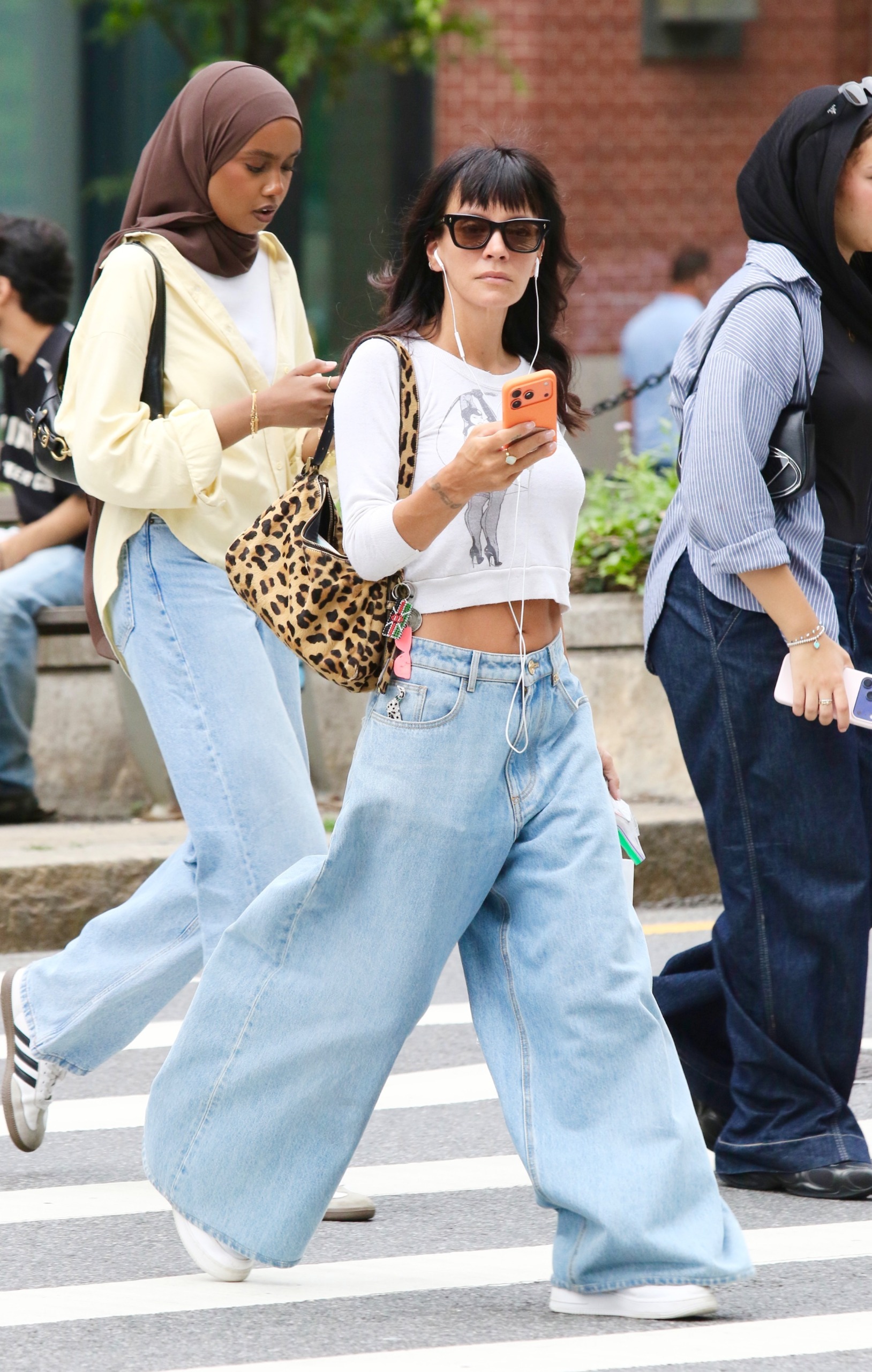Lilly allen wears a white top, leopard-print bag, extra-wide-leg jeans, and white sneakers.