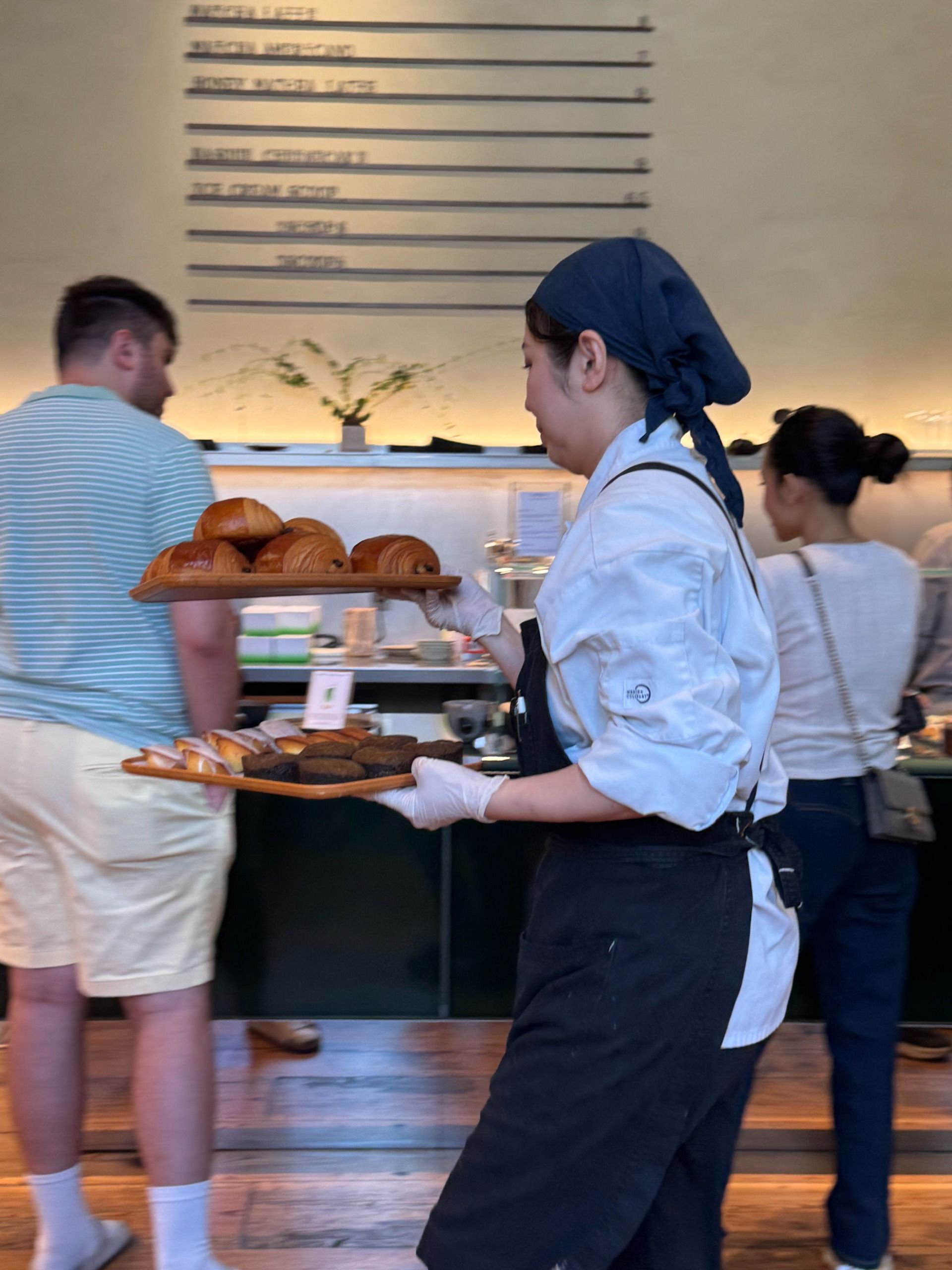 Server carrying trays of pastries at a cafe.