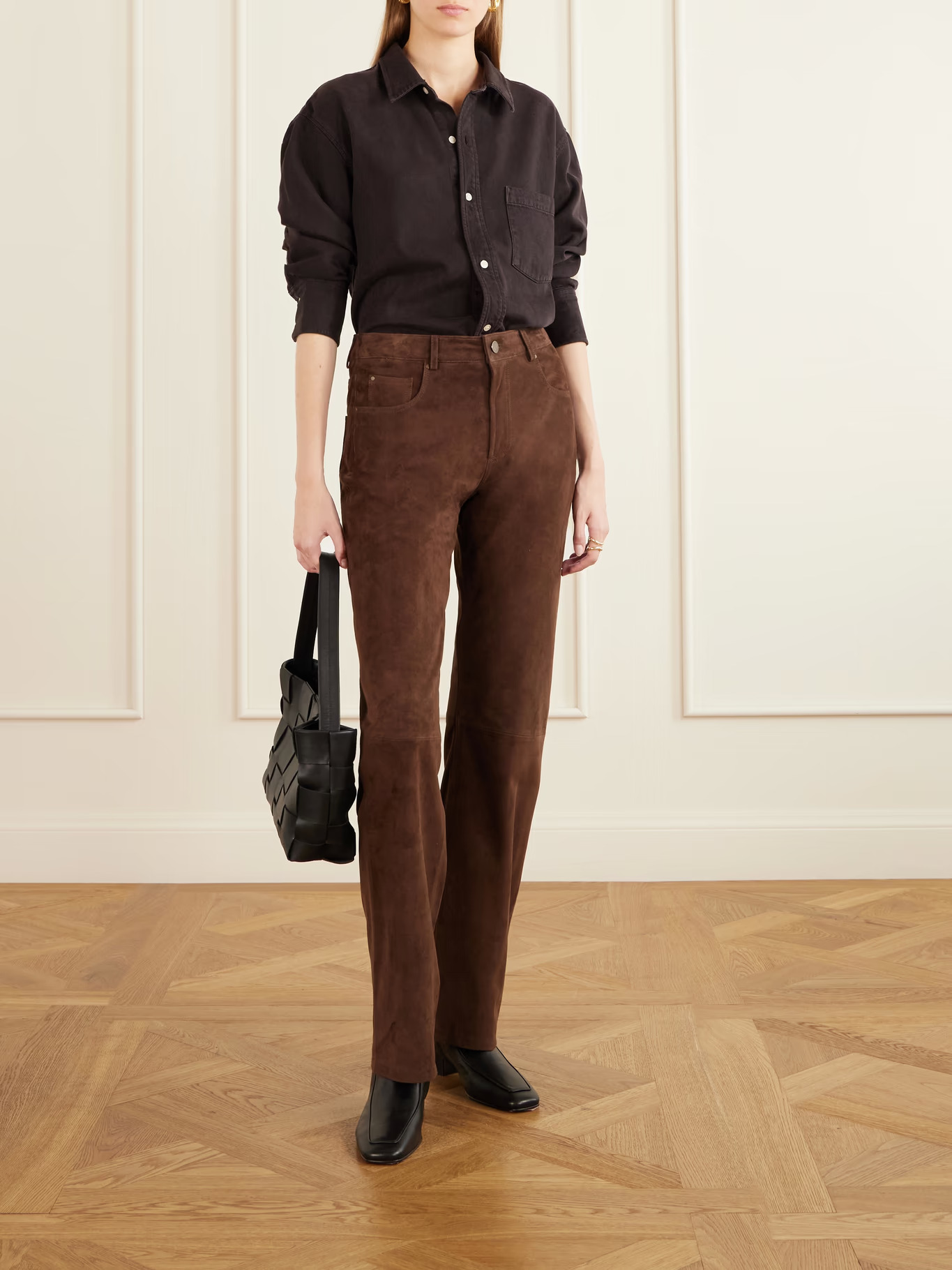 An image of a model wearing brown suede trousers, a brown button-down top and black boots