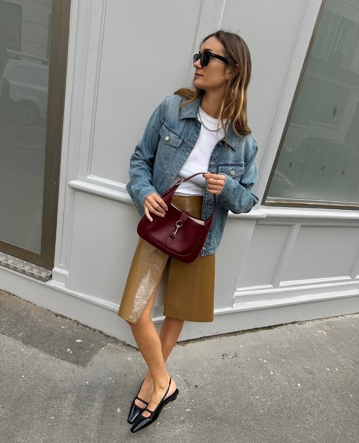 @annelauremais wearing a knee-length skirt, white T-shirt, jean jacket, burgundy handbag, and black slingback flats