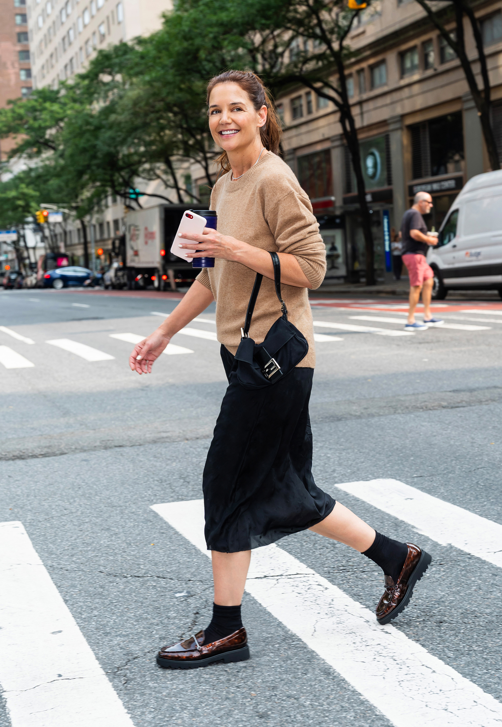 Katie holmes wears a falconeri sweater with a black skirt, black bag, and burgundy loafers.