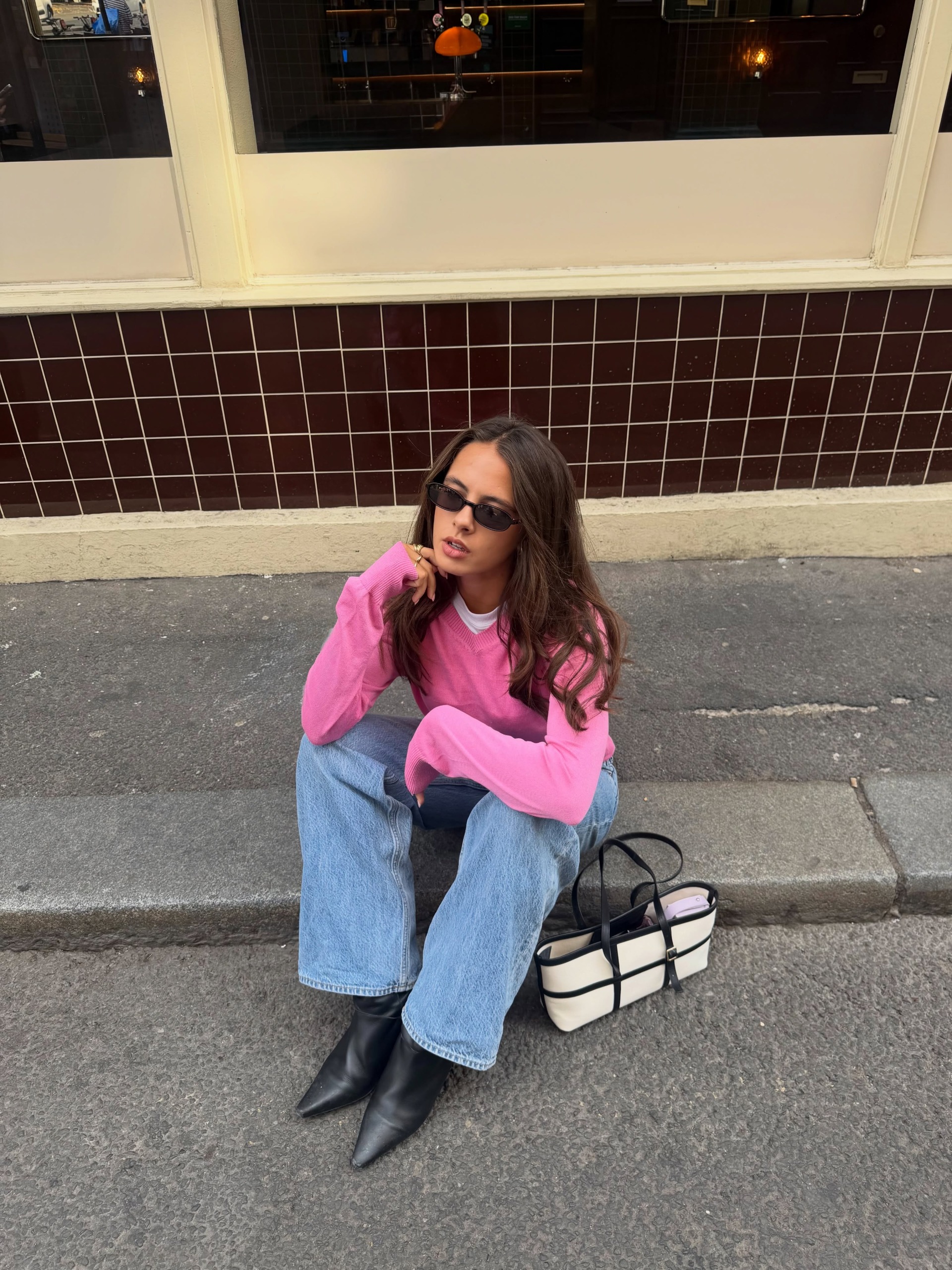 Influencer Tia Dewitt wearing a pink v-neck jumper.