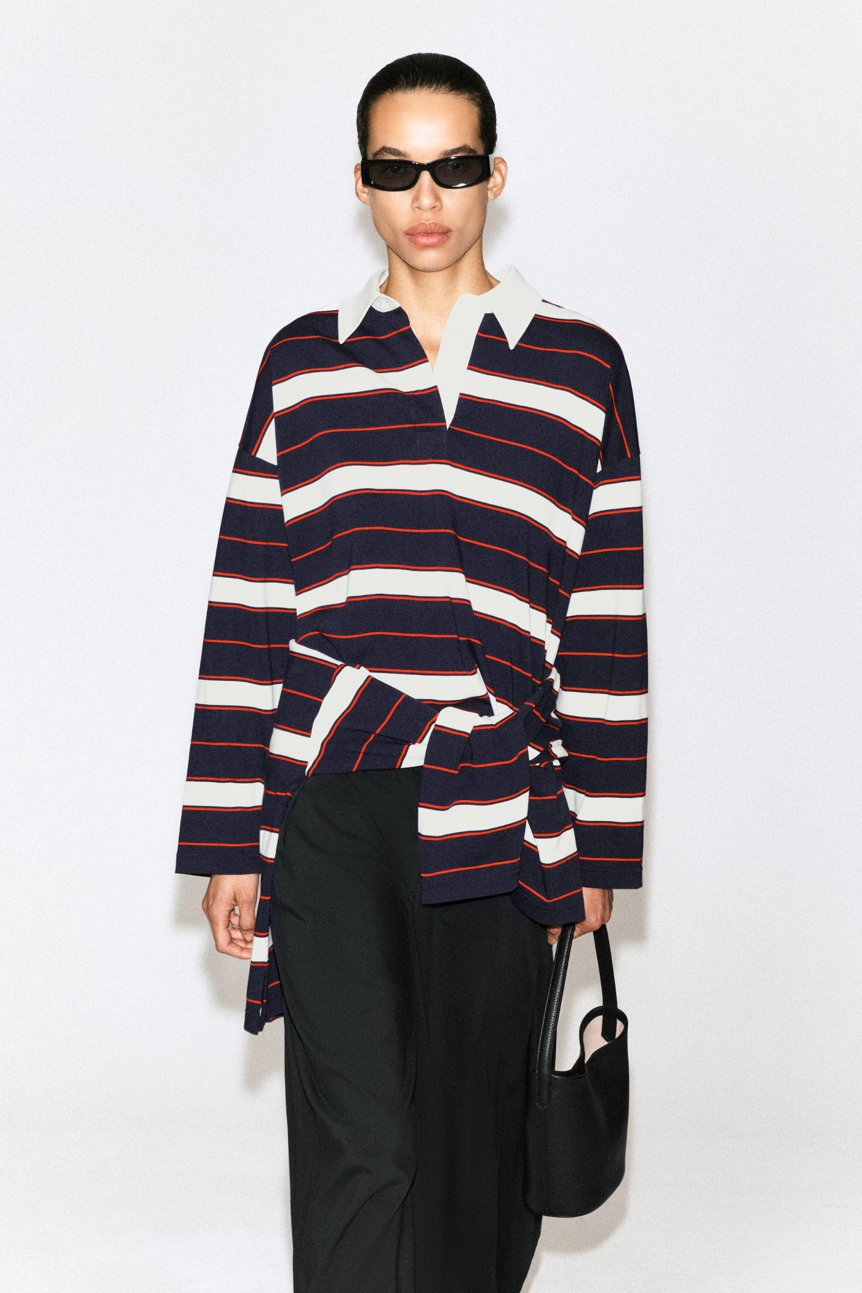 A model wearing a red and navy striped Cos rugby shirt.
