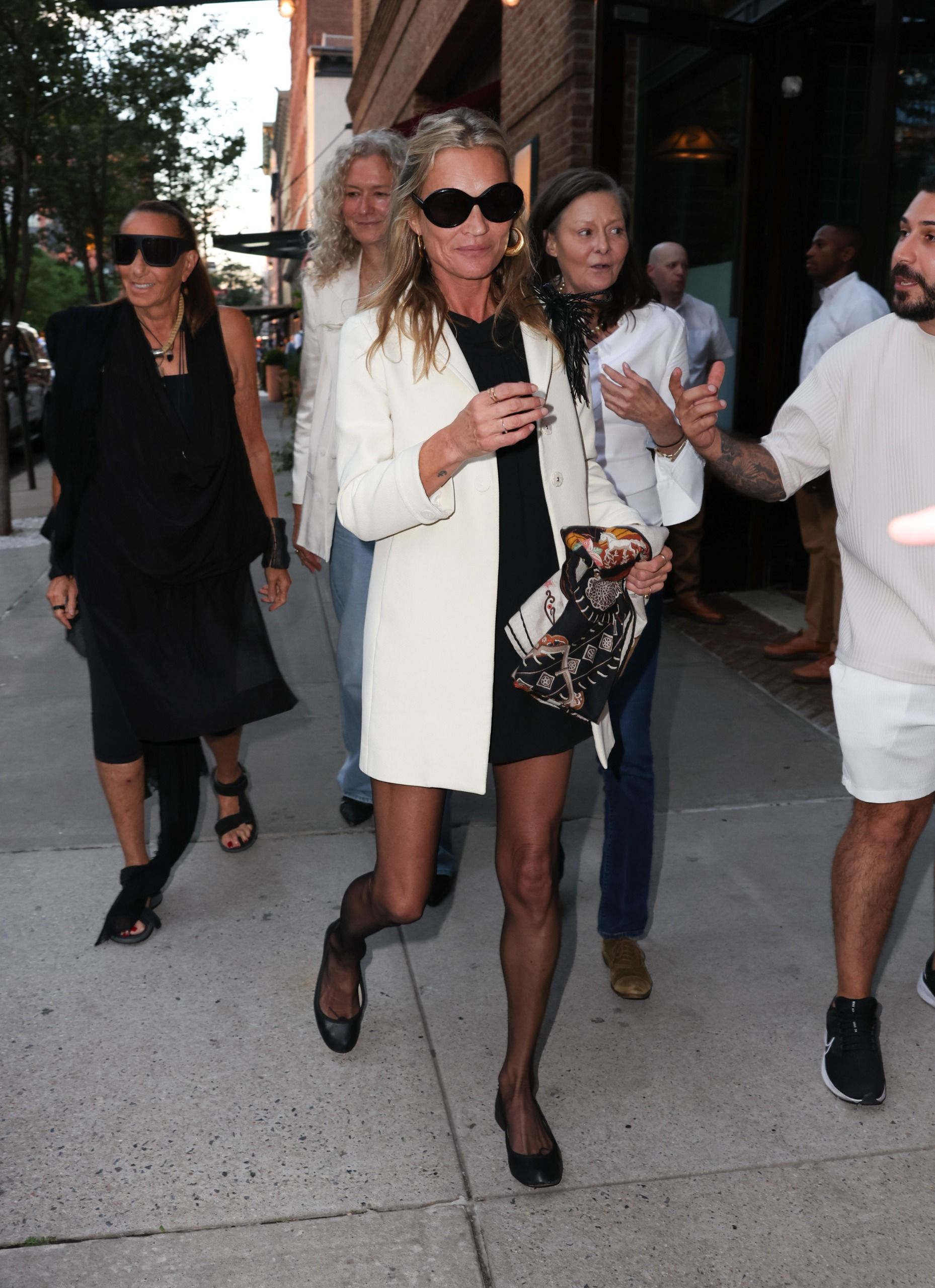 An image of Kate Moss wearing a white blazer with a black mini dress, black tights and black ballet flats whilst in New York.